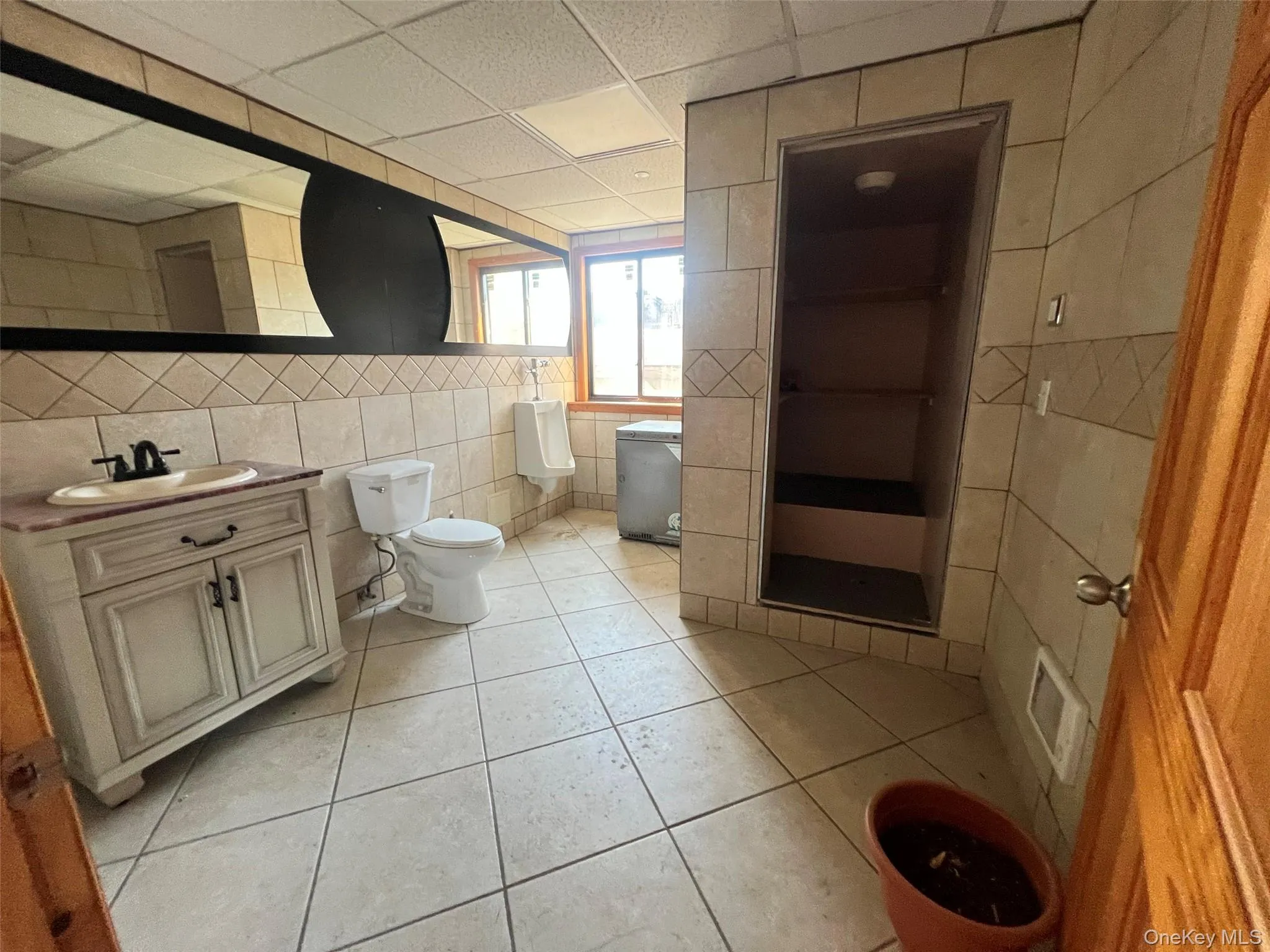 Bathroom featuring tile walls, vanity, light tile patterned flooring, and a drop ceiling Bathroom featuring tile walls, vanity, light tile patterned flooring, and a drop ceiling