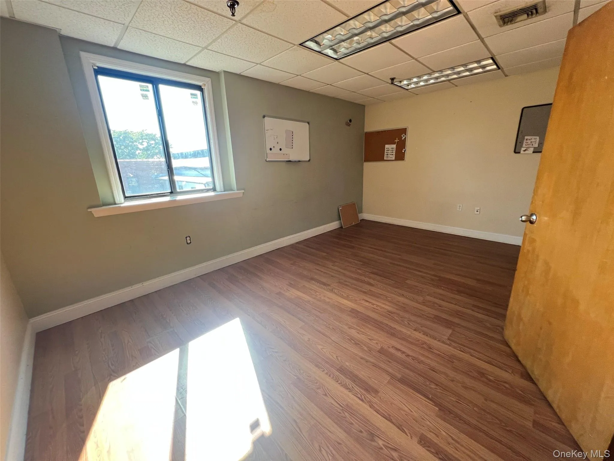 Unfurnished room featuring a paneled ceiling and dark wood-style flooring Unfurnished room featuring a paneled ceiling and dark wood-style flooring