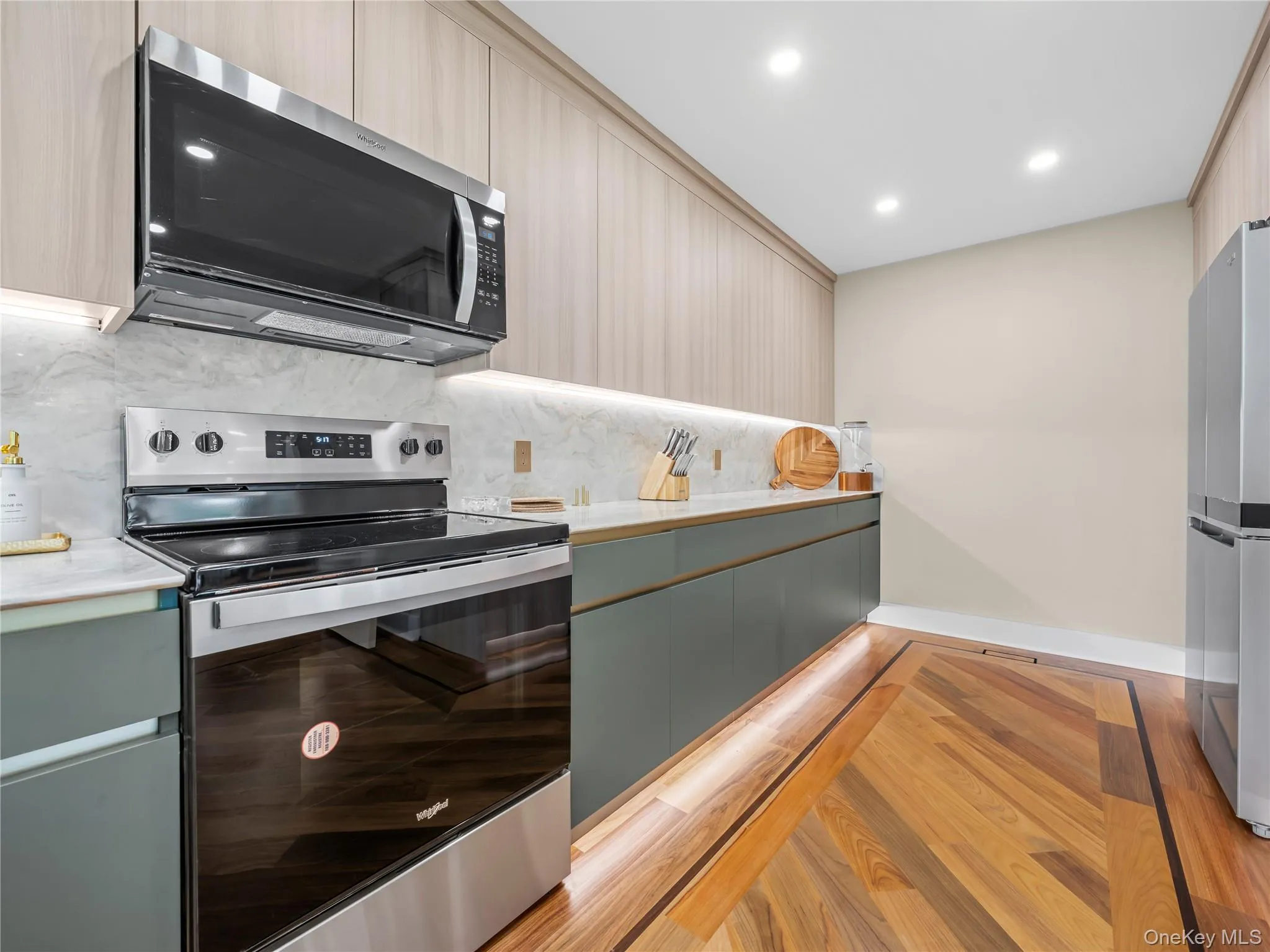 Kitchen featuring appliances with stainless steel finishes, light wood-type flooring, recessed lighting, decorative backsplash, and modern cabinets Kitchen featuring appliances with stainless steel finishes, light wood-type flooring, recessed lighting, decorative backsplash, and modern cabinets