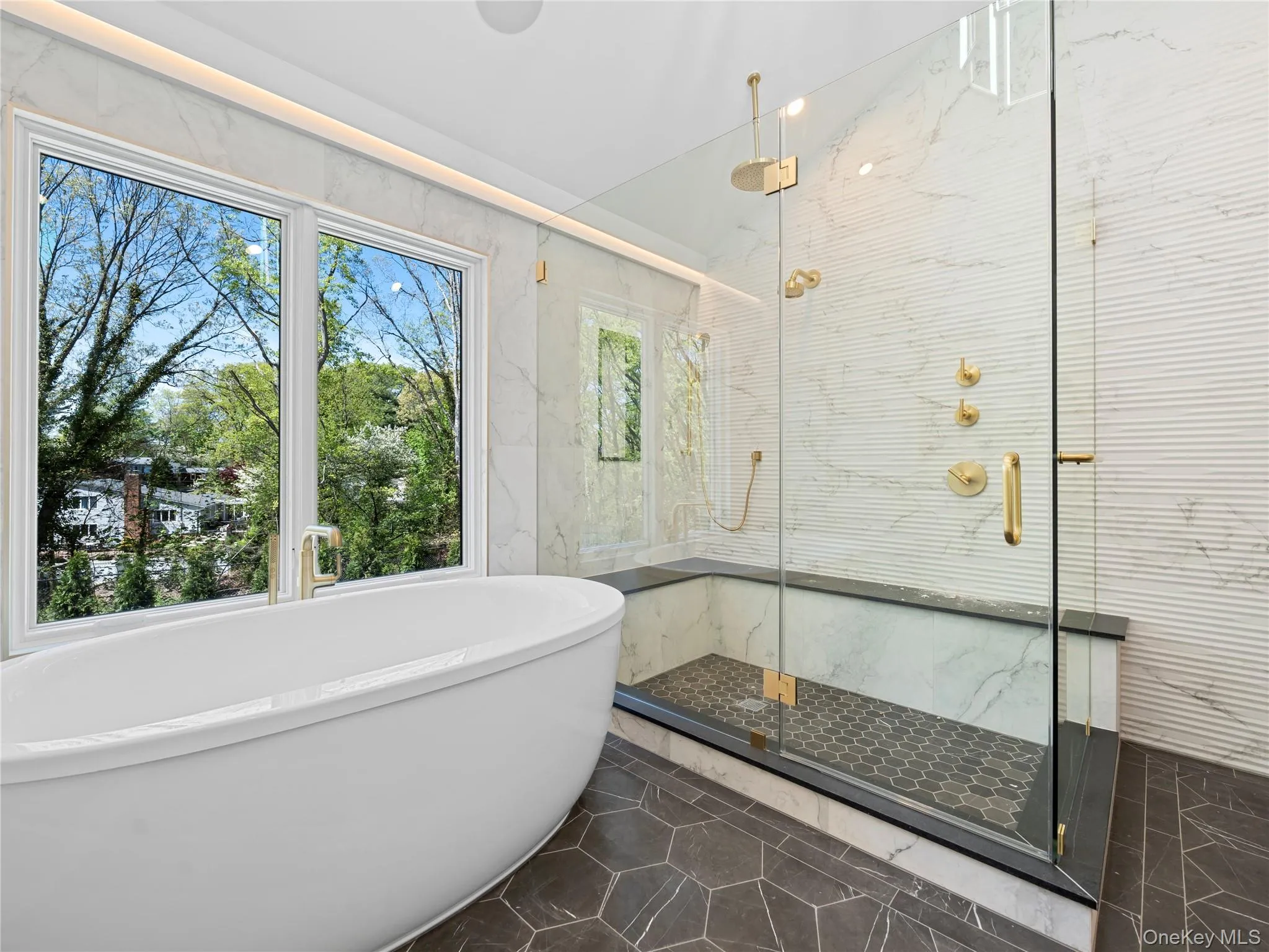 Bathroom featuring a marble finish shower, a freestanding tub, tile walls, and stone wall Bathroom featuring a marble finish shower, a freestanding tub, tile walls, and stone wall