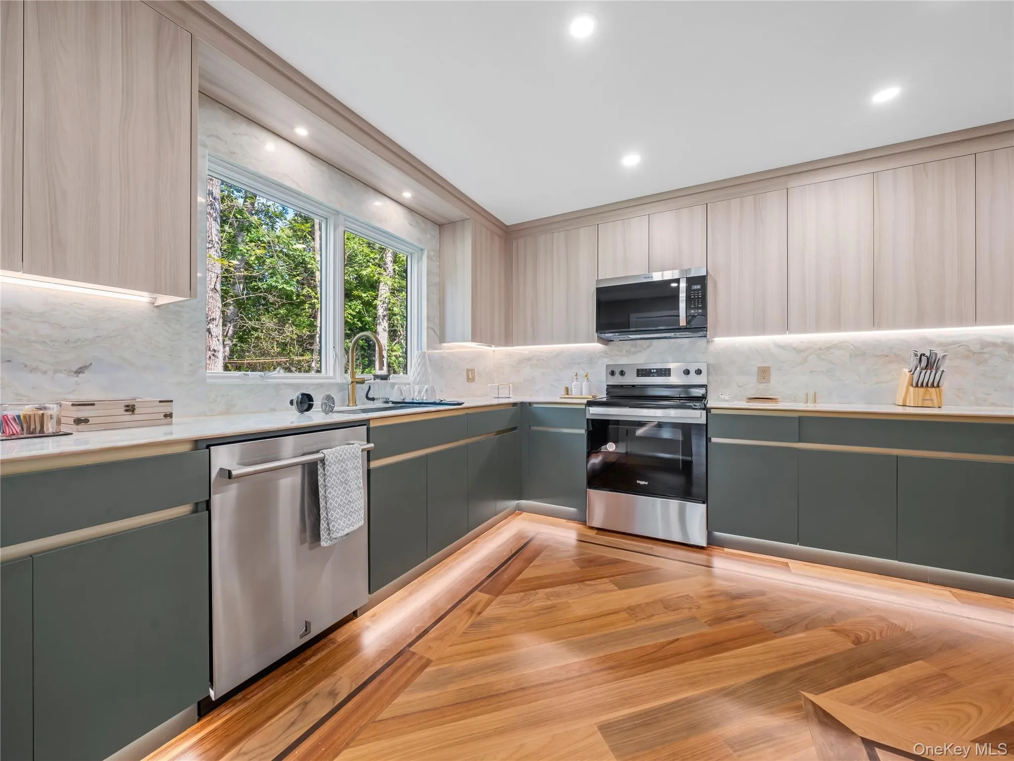 Kitchen featuring appliances with stainless steel finishes, modern cabinets, tasteful backsplash, recessed lighting, and light wood-type flooring Kitchen featuring appliances with stainless steel finishes, modern cabinets, tasteful backsplash, recessed lighting, and light wood-type flooring