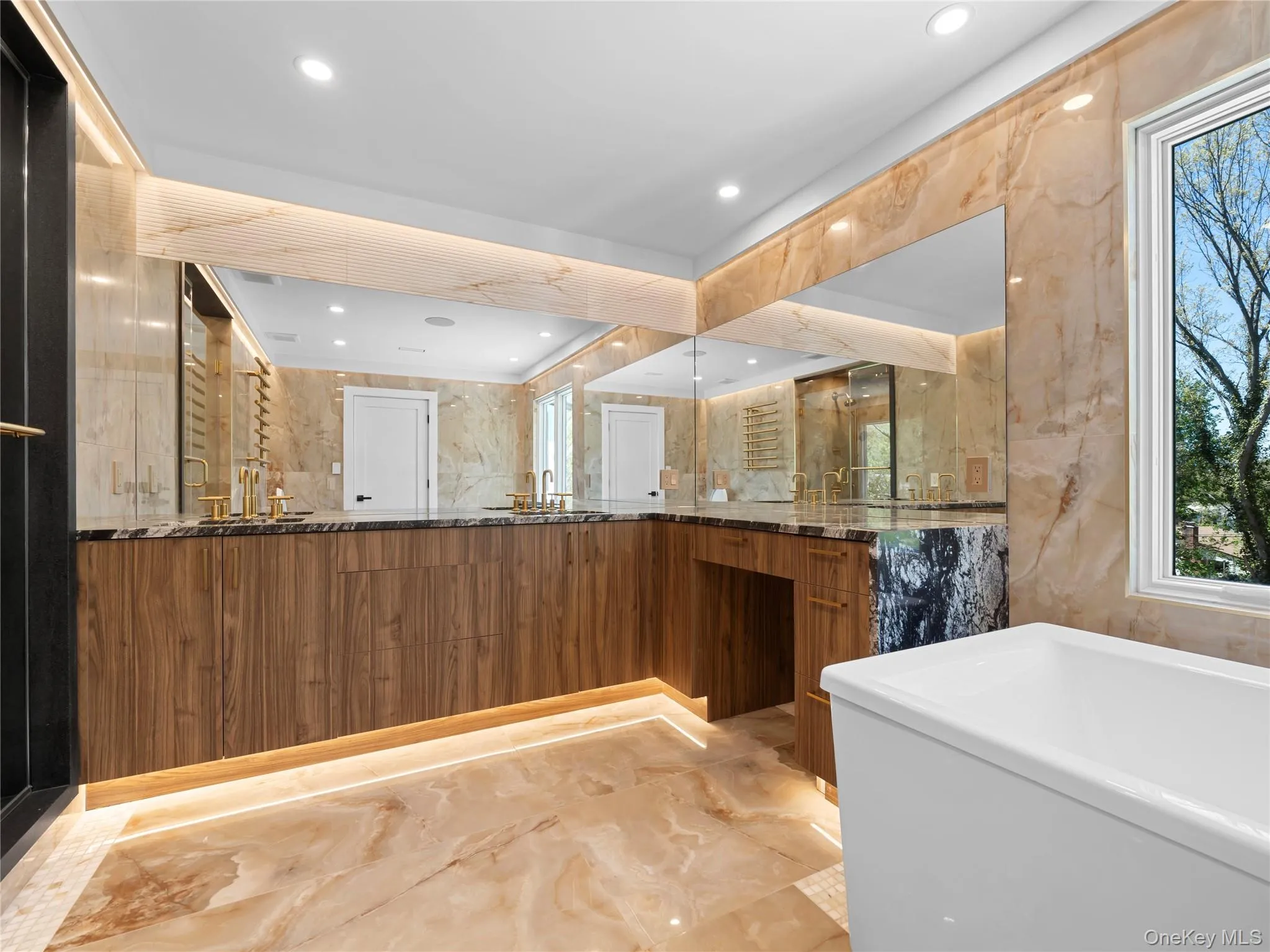 Bathroom featuring light marble finish floors, stone wall, double vanity, recessed lighting, and a soaking tub Bathroom featuring light marble finish floors, stone wall, double vanity, recessed lighting, and a soaking tub