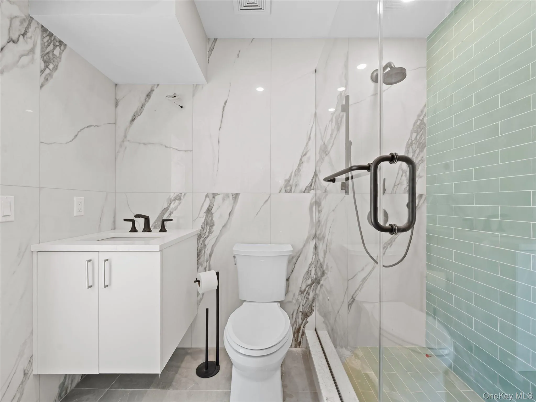 Bathroom featuring tile walls, vanity, and a marble finish shower Bathroom featuring tile walls, vanity, and a marble finish shower