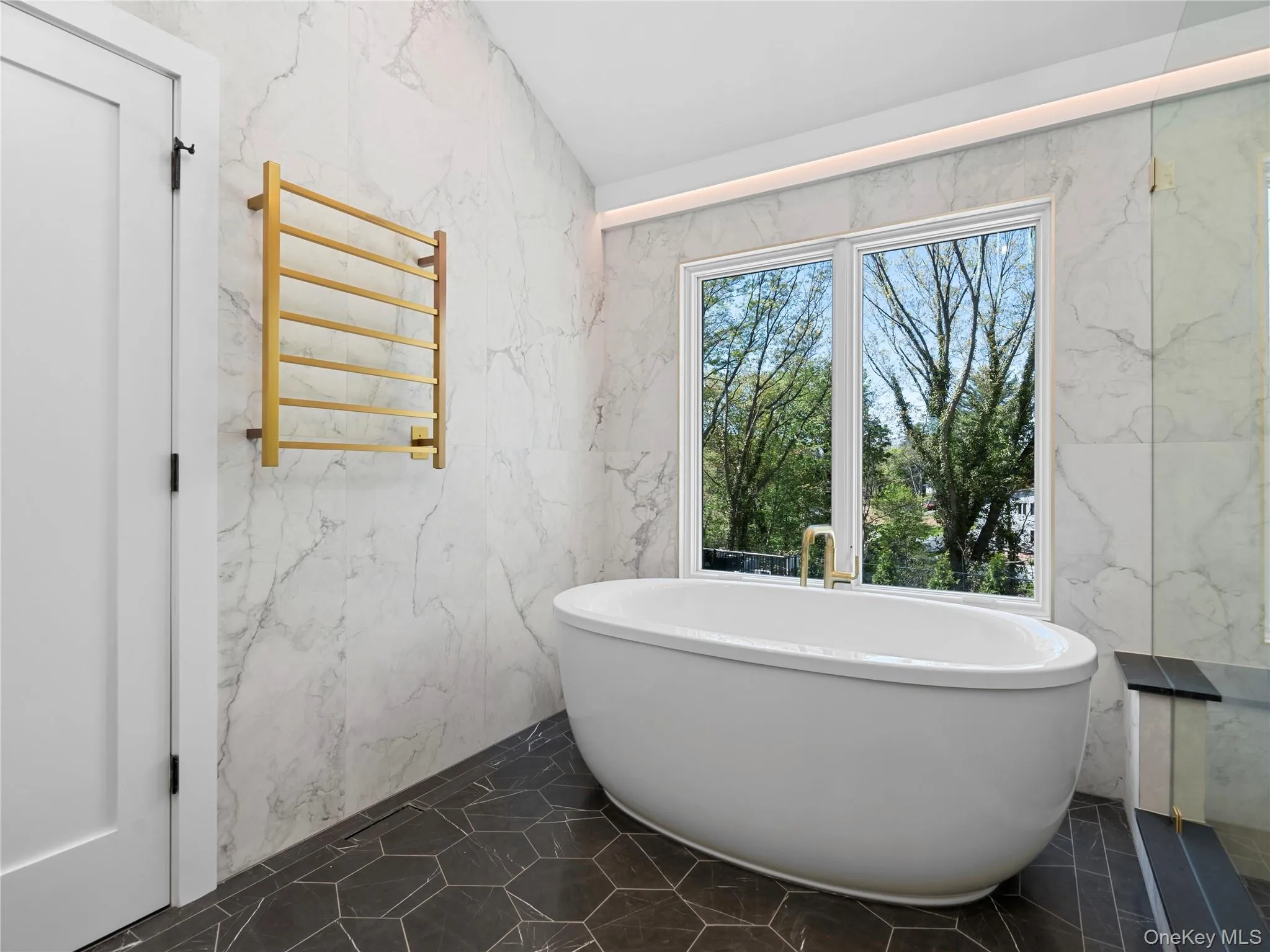 Bathroom with radiator heating unit, a towel warming rack, a freestanding bath, stone wall, and tile walls Bathroom with radiator heating unit, a towel warming rack, a freestanding bath, stone wall, and tile walls