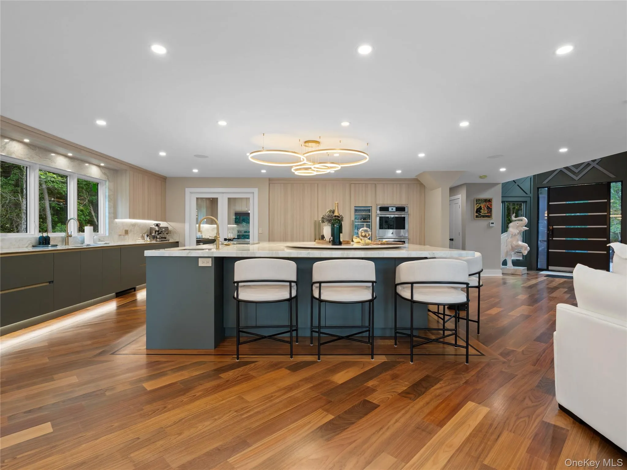 Kitchen with a breakfast bar area, a spacious island, open floor plan, dark wood-style flooring, and light stone countertops Kitchen with a breakfast bar area, a spacious island, open floor plan, dark wood-style flooring, and light stone countertops