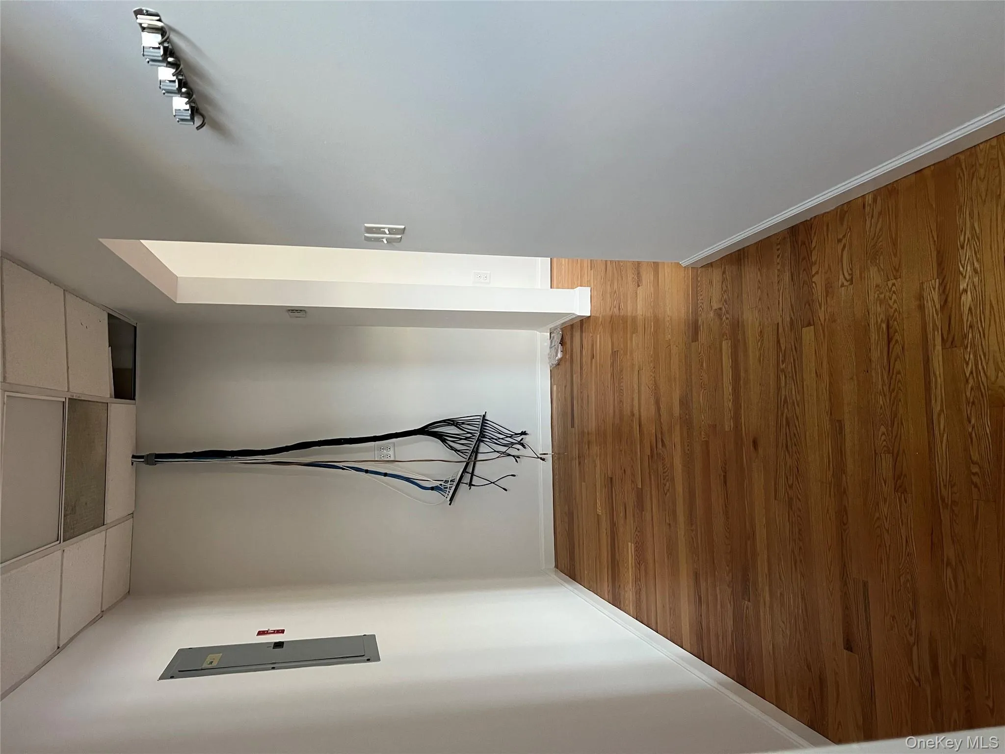 Hallway featuring a paneled ceiling, wood finished floors, and electric panel Hallway featuring a paneled ceiling, wood finished floors, and electric panel
