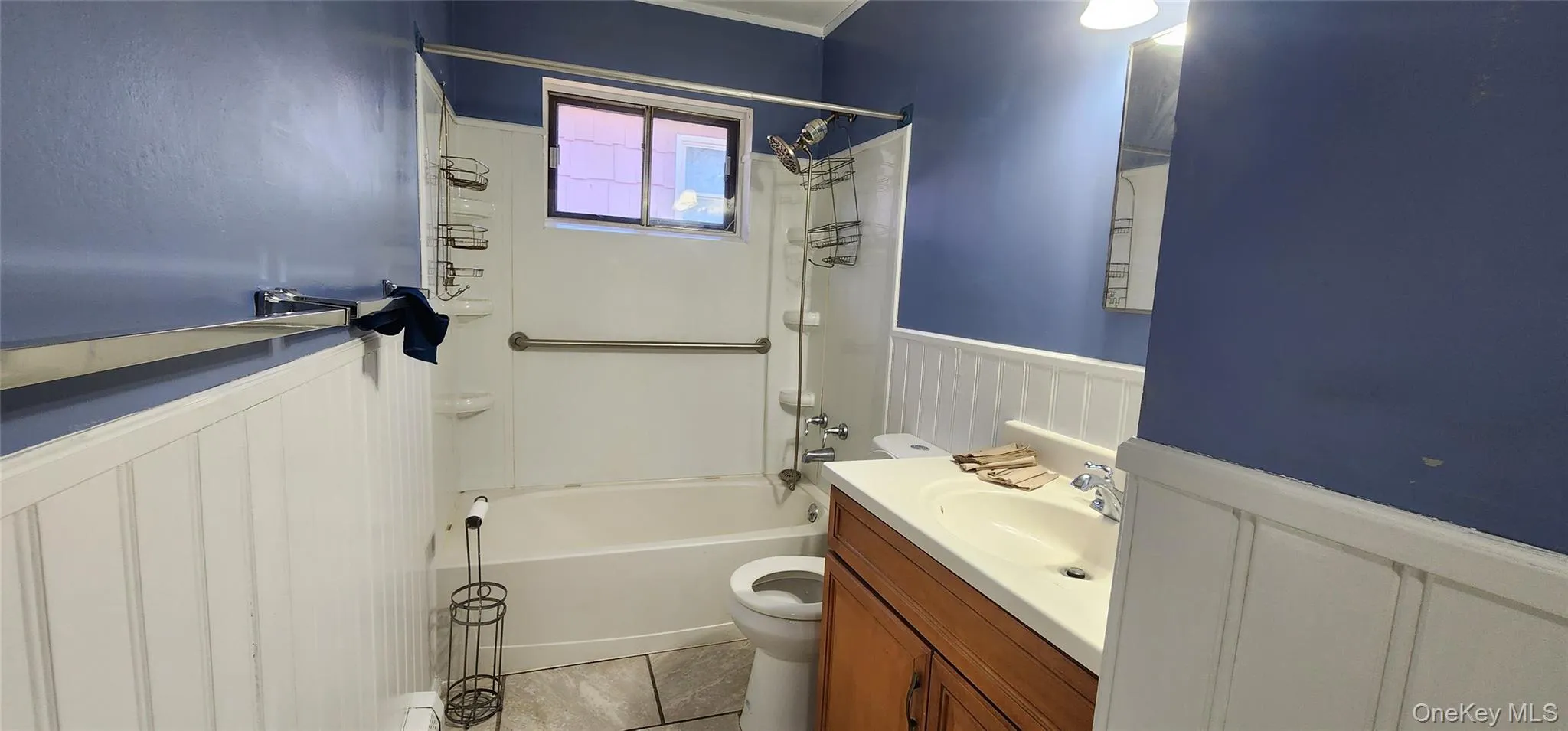 Bathroom featuring wainscoting, a decorative wall, vanity, and shower / washtub combination Bathroom featuring wainscoting, a decorative wall, vanity, and shower / washtub combination
