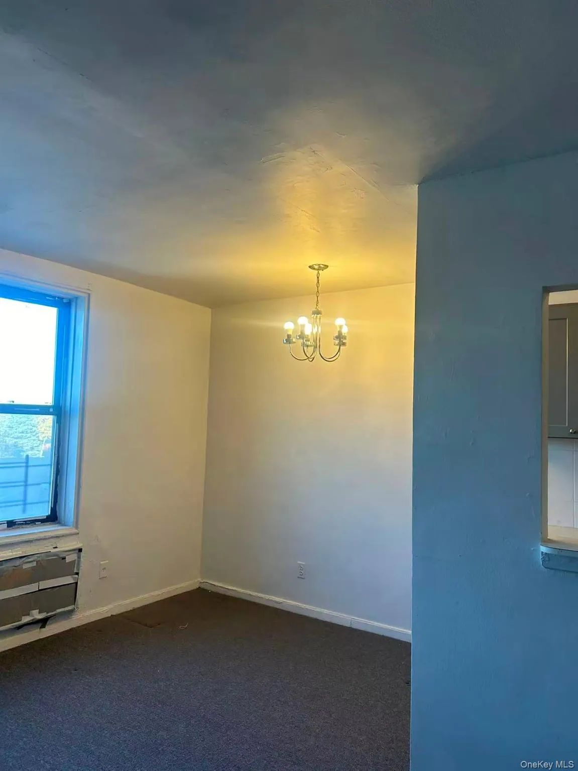 Empty room with a chandelier and dark colored carpet Empty room with a chandelier and dark colored carpet