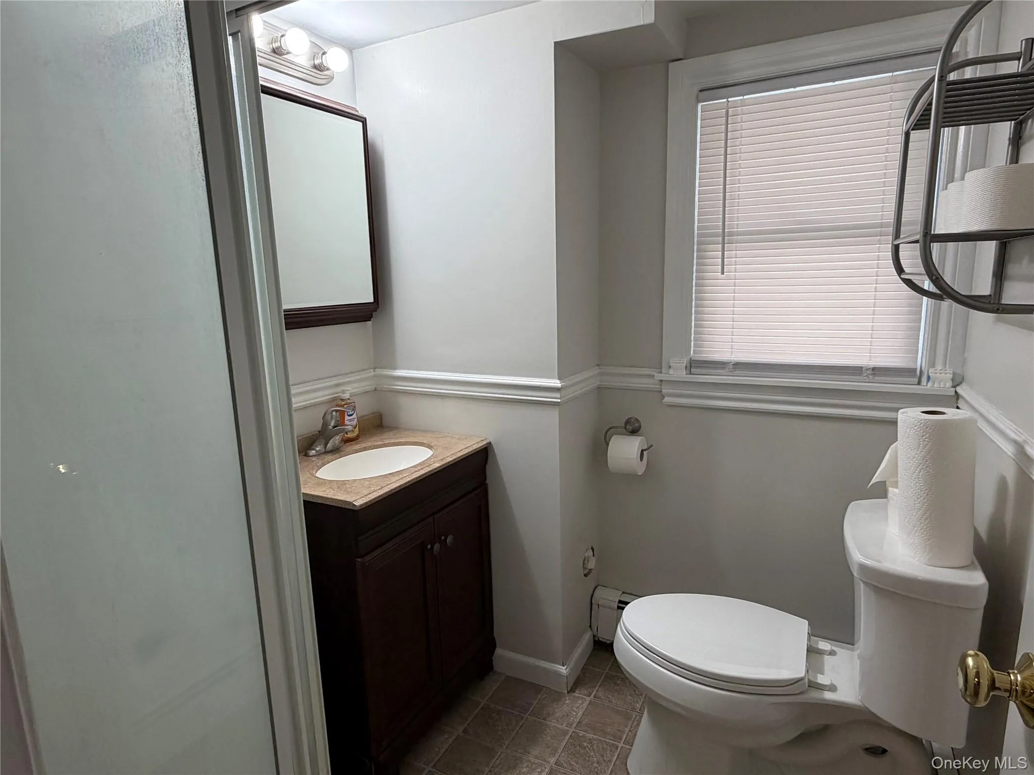 Bathroom with vanity, a baseboard radiator, and dark tile patterned floors Bathroom with vanity, a baseboard radiator, and dark tile patterned floors