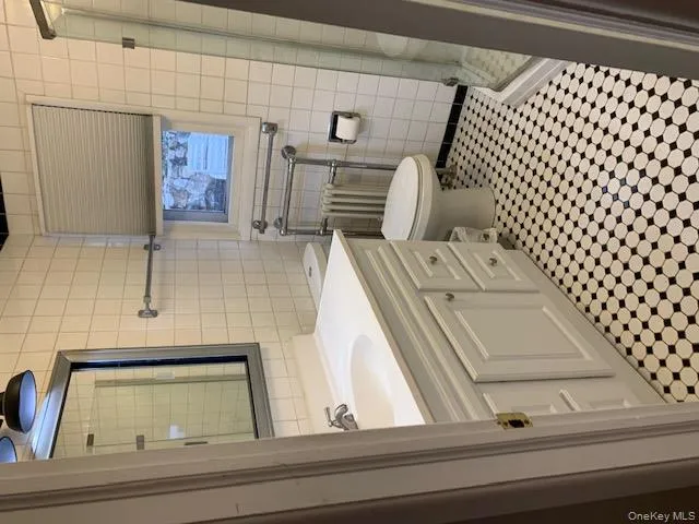 Bathroom with vanity, a shower stall, tile walls, and radiator heating unit Bathroom with vanity, a shower stall, tile walls, and radiator heating unit