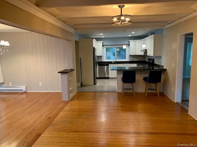 Kitchen with a chandelier, light wood-style floors, wooden walls, hanging light fixtures, and appliances with stainless steel finishes Kitchen with a chandelier, light wood-style floors, wooden walls, hanging light fixtures, and appliances with stainless steel finishes