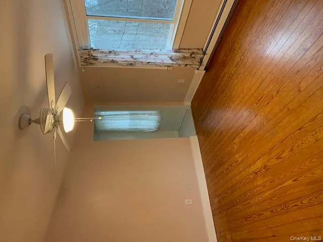 Unfurnished room featuring baseboard heating, hardwood / wood-style flooring, and a ceiling fan Unfurnished room featuring baseboard heating, hardwood / wood-style flooring, and a ceiling fan