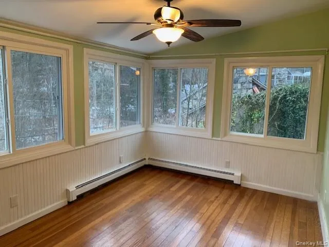 Unfurnished bedroom featuring hardwood / wood-style floors, plenty of natural light, baseboard heating, and vaulted ceiling Unfurnished bedroom featuring hardwood / wood-style floors, plenty of natural light, baseboard heating, and vaulted ceiling