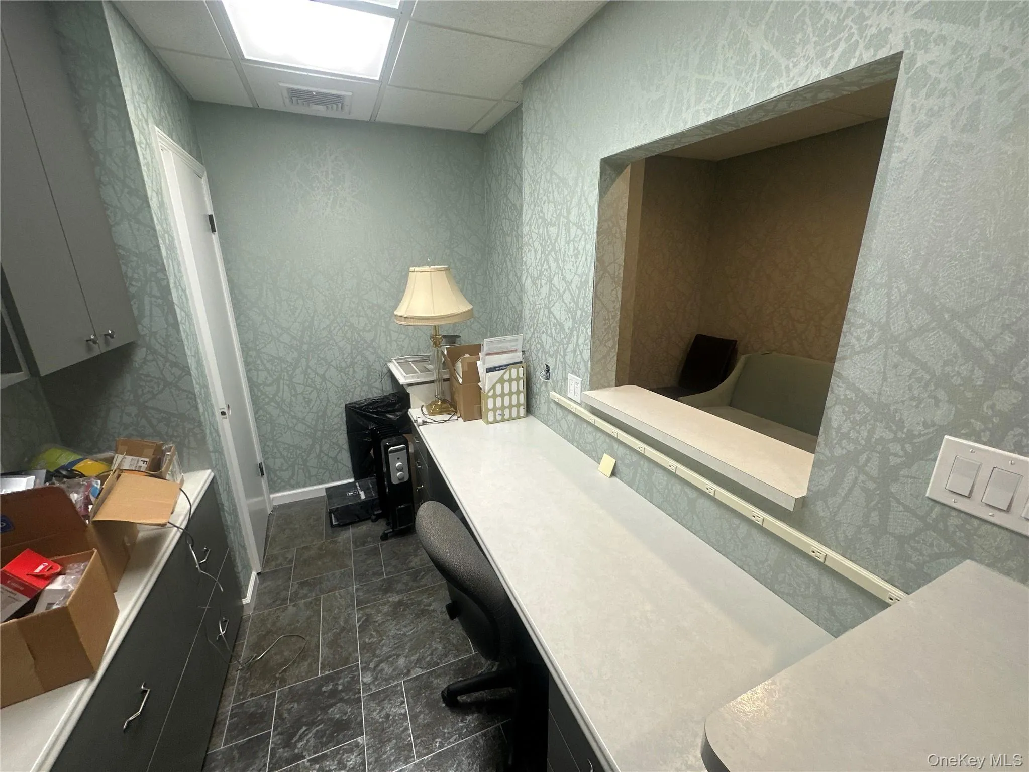 Home office with a drop ceiling, stone finish floors, and wallpapered walls Home office with a drop ceiling, stone finish floors, and wallpapered walls