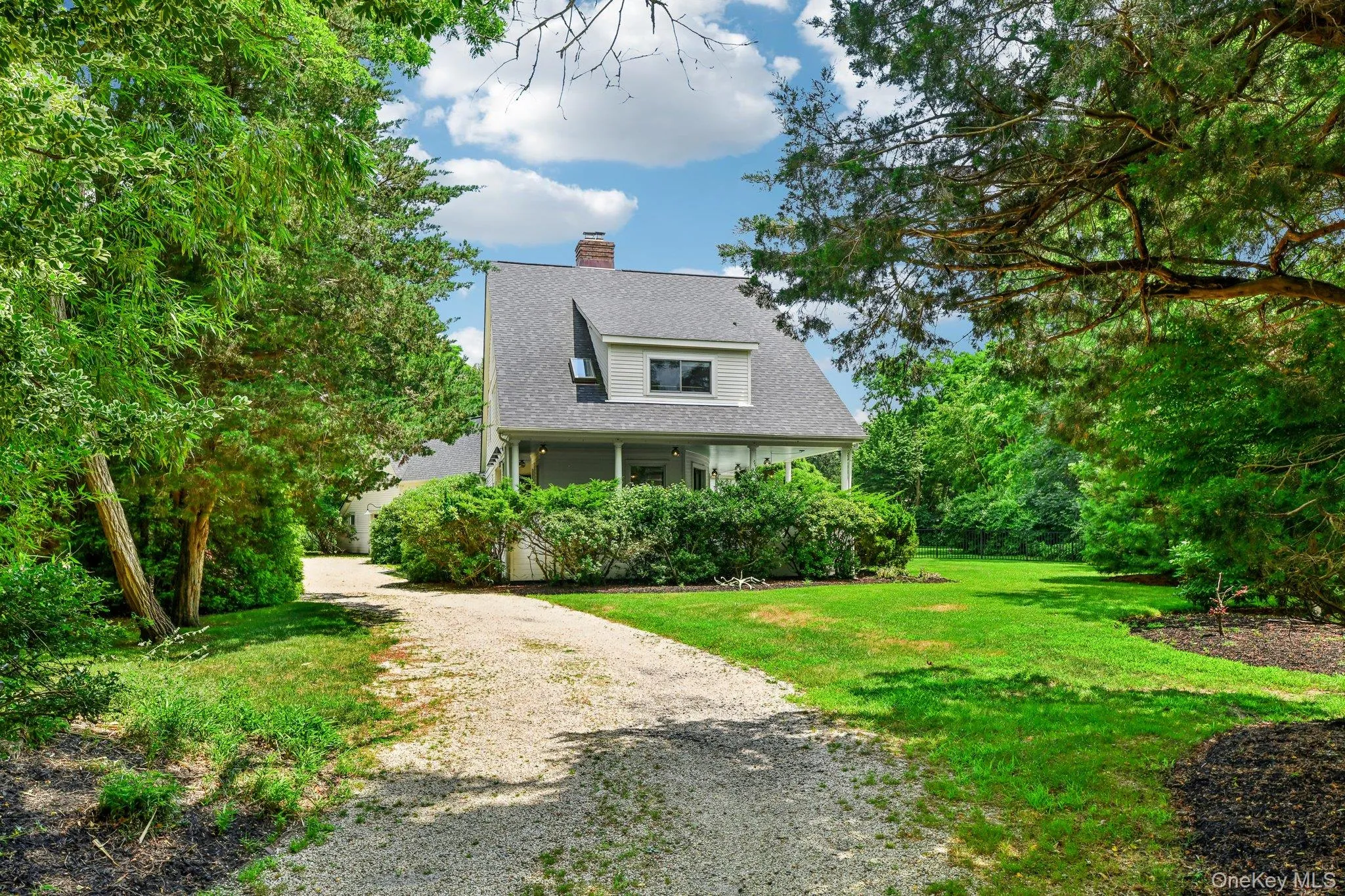 View of front of property with gravel driveway, a front yard, a chimney, roof with shingles, and covered porch View of front of property with gravel driveway, a front yard, a chimney, roof with shingles, and covered porch