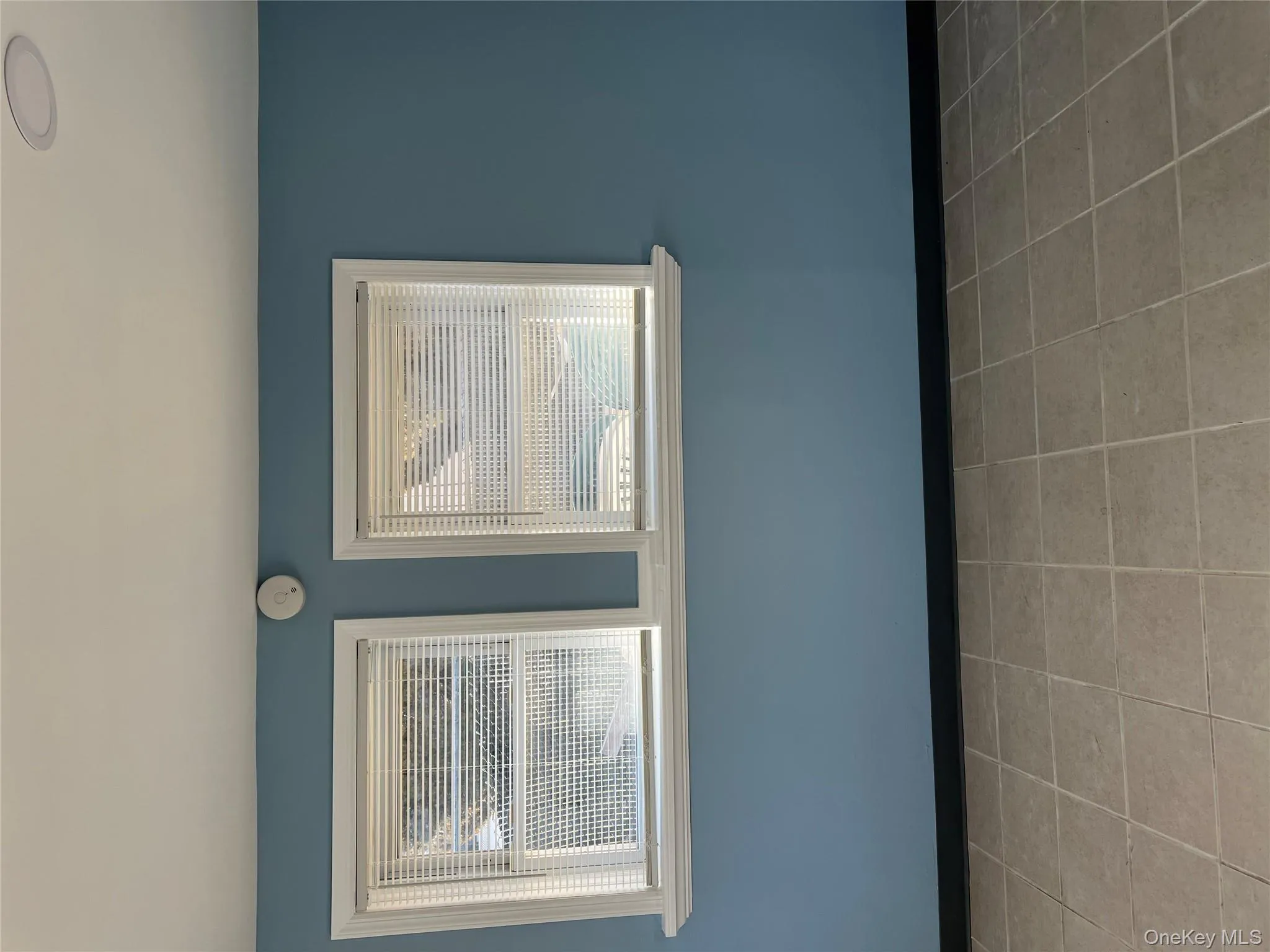 Unfurnished room with light tile patterned floors and a smoke detector Unfurnished room with light tile patterned floors and a smoke detector