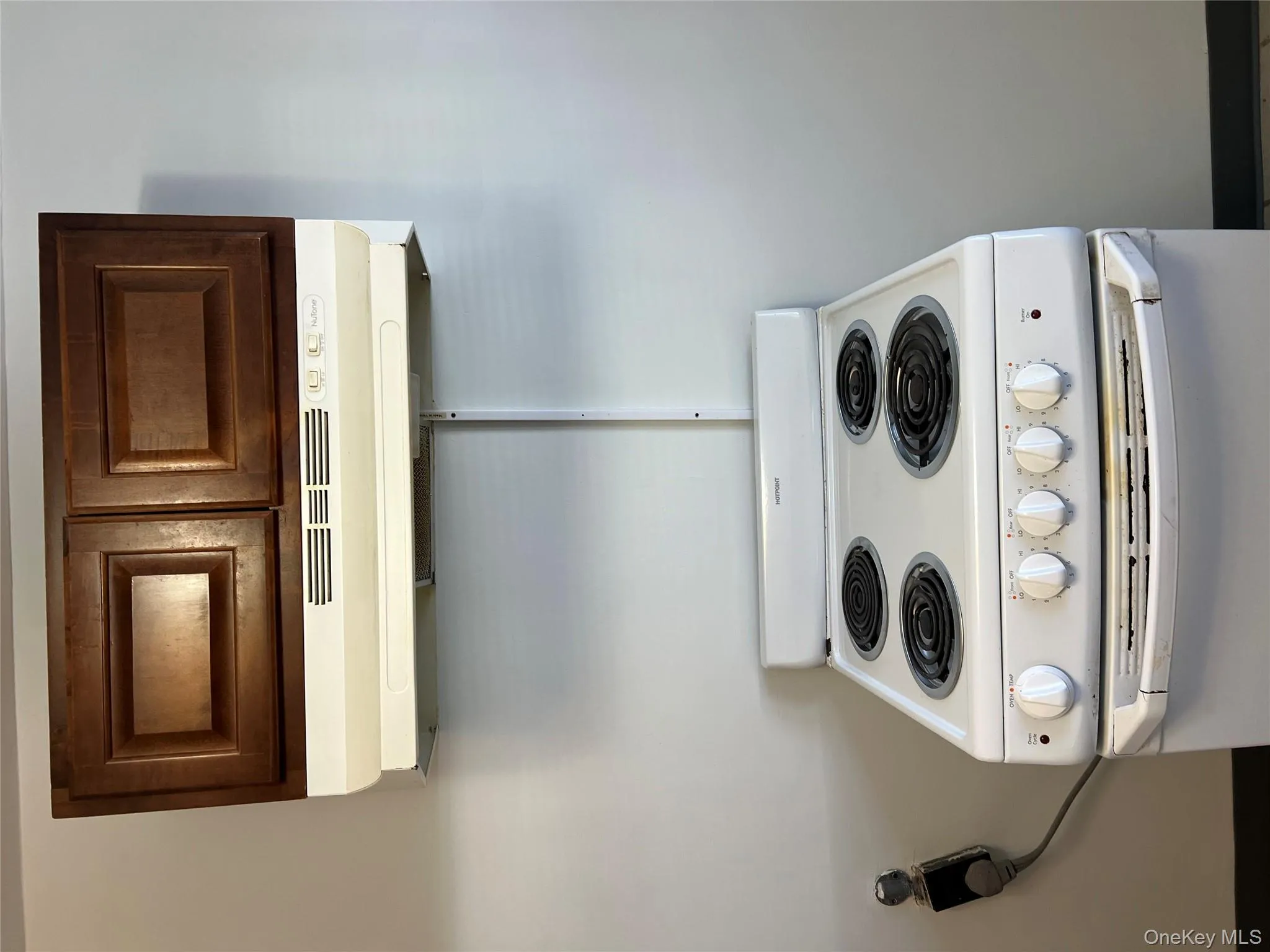 Kitchen view of white stove, range hood, and dark brown cabinetry Kitchen view of white stove, range hood, and dark brown cabinetry