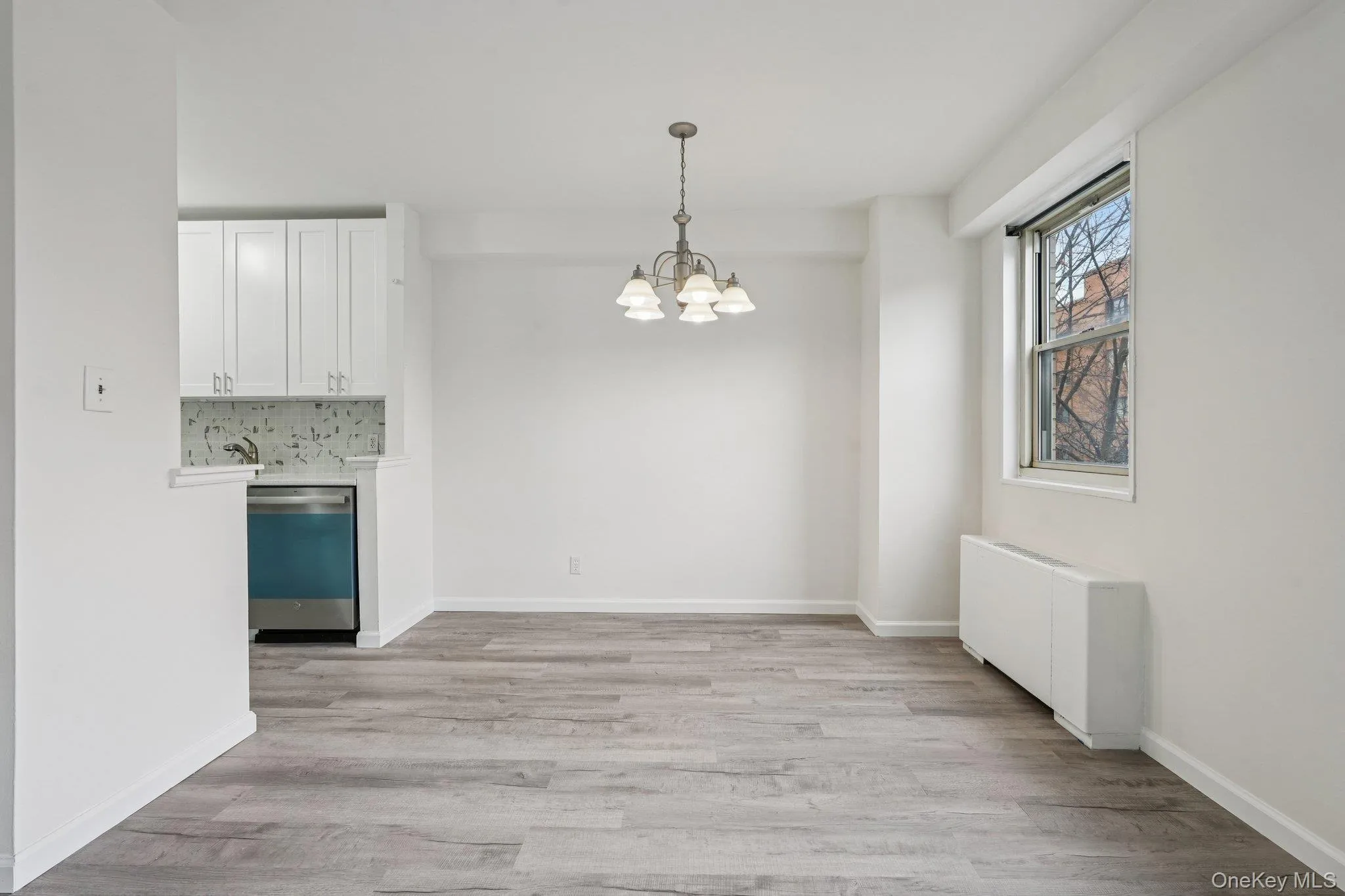 Unfurnished dining area featuring radiator, a chandelier, and light wood-style floors Unfurnished dining area featuring radiator, a chandelier, and light wood-style floors