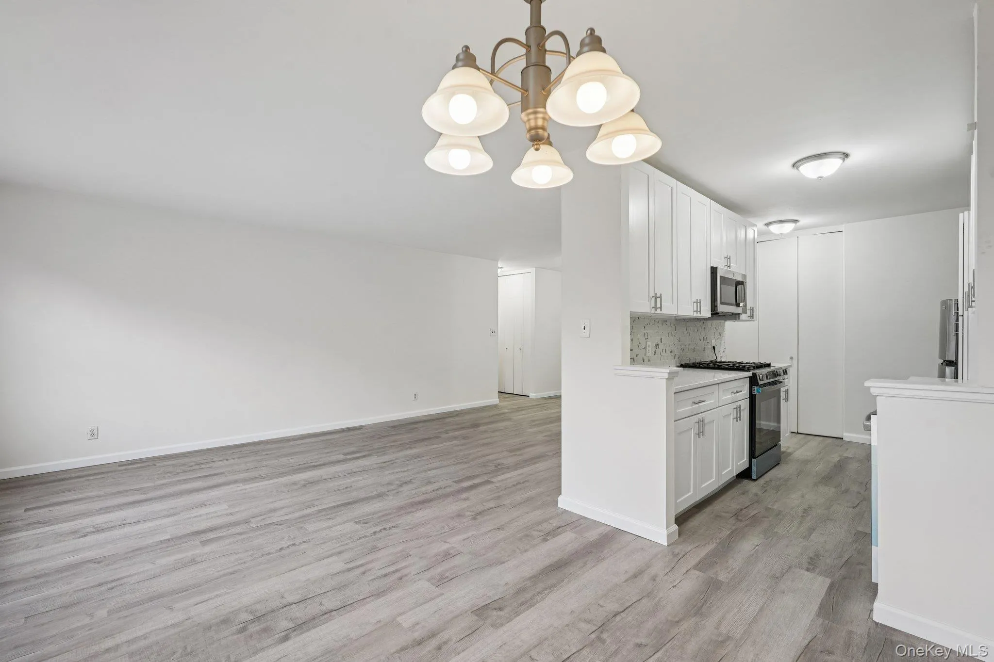 Kitchen featuring white cabinets, black gas range oven, a chandelier, and hanging light fixtures Kitchen featuring white cabinets, black gas range oven, a chandelier, and hanging light fixtures