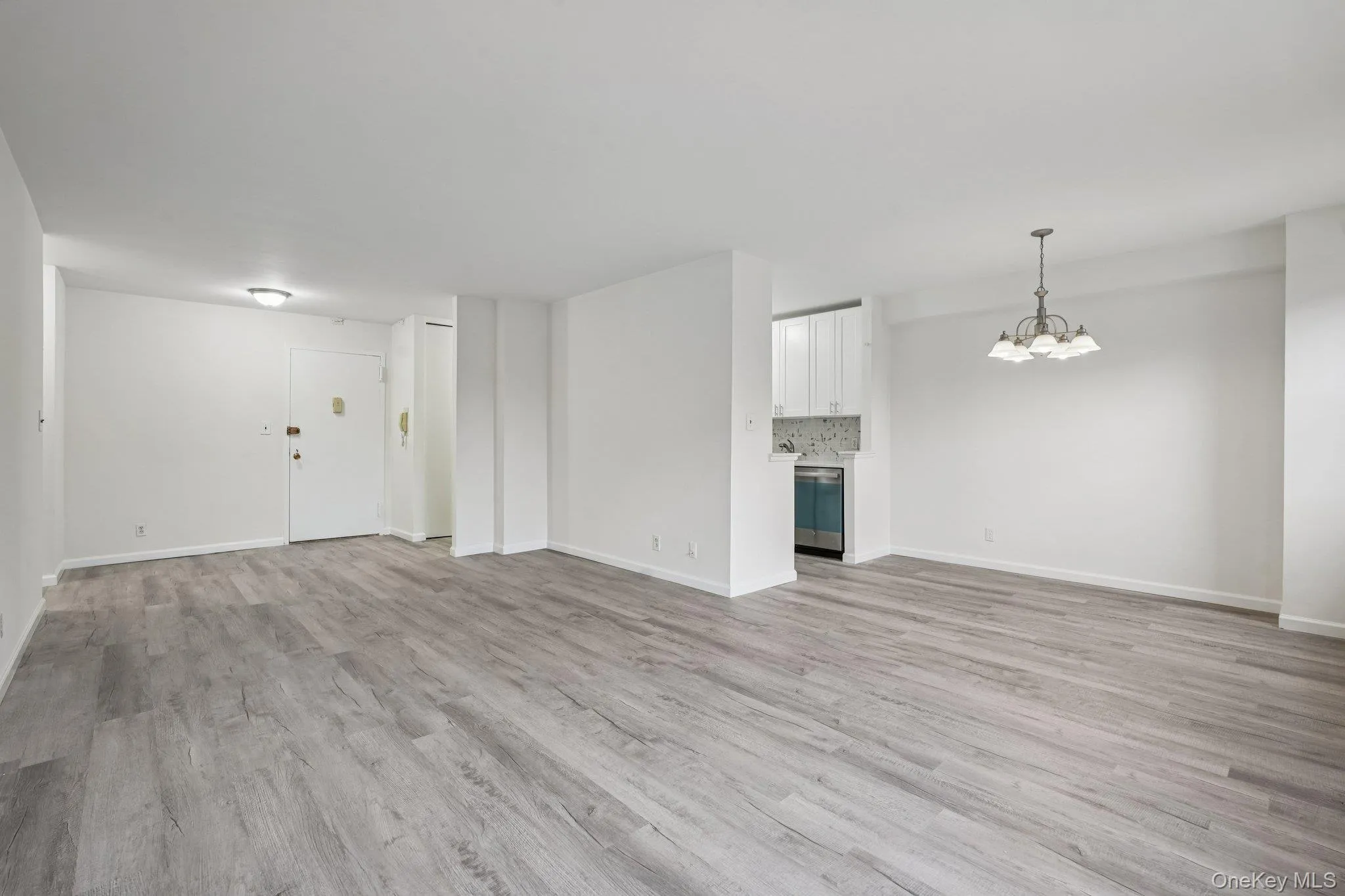 Unfurnished living room featuring a chandelier and light wood finished floors Unfurnished living room featuring a chandelier and light wood finished floors