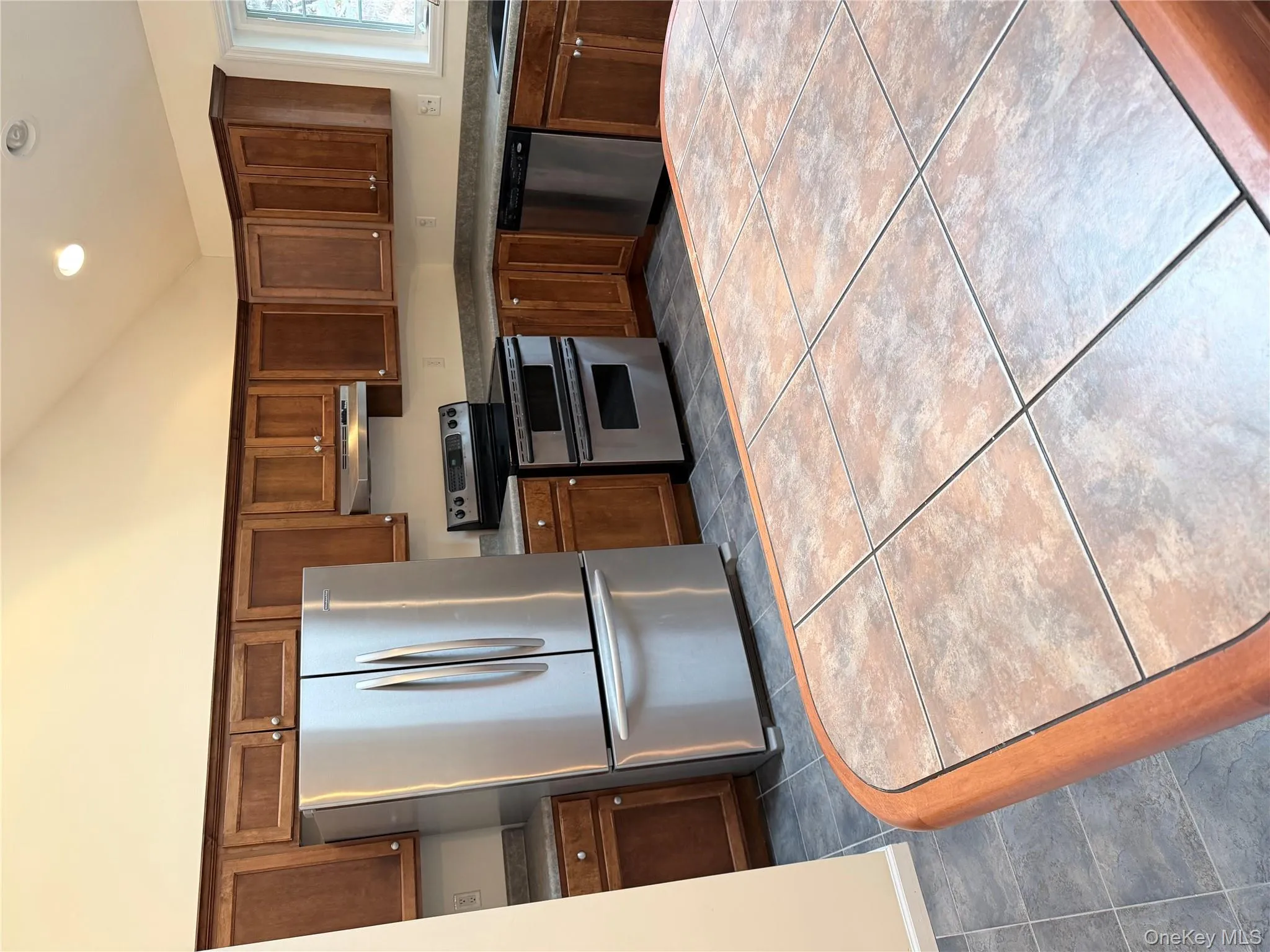 Kitchen featuring stainless steel appliances, high vaulted ceiling, dark countertops, exhaust hood, and recessed lighting Kitchen featuring stainless steel appliances, high vaulted ceiling, dark countertops, exhaust hood, and recessed lighting