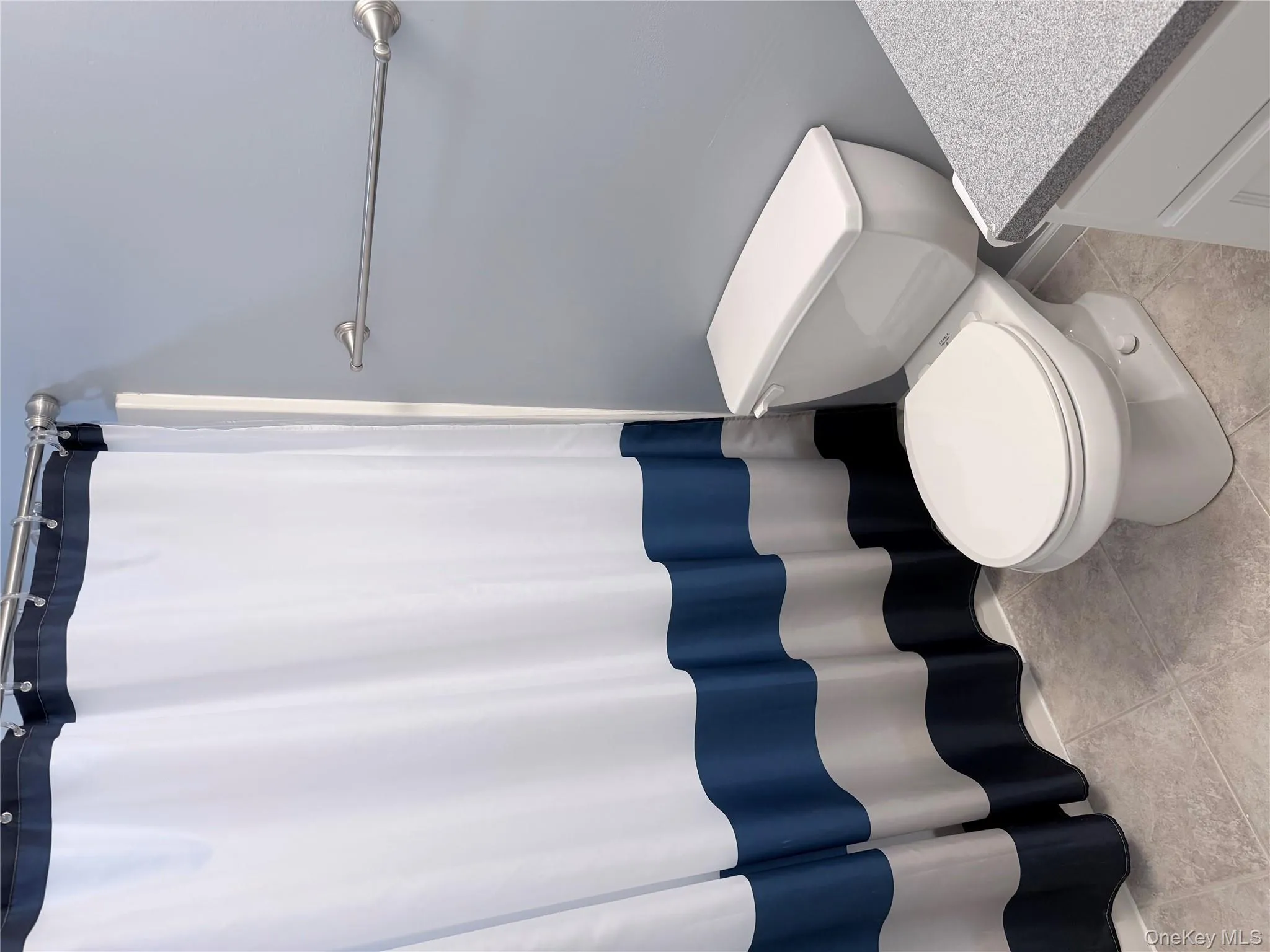 Full bath featuring curtained shower, vanity, and light tile patterned flooring Full bath featuring curtained shower, vanity, and light tile patterned flooring