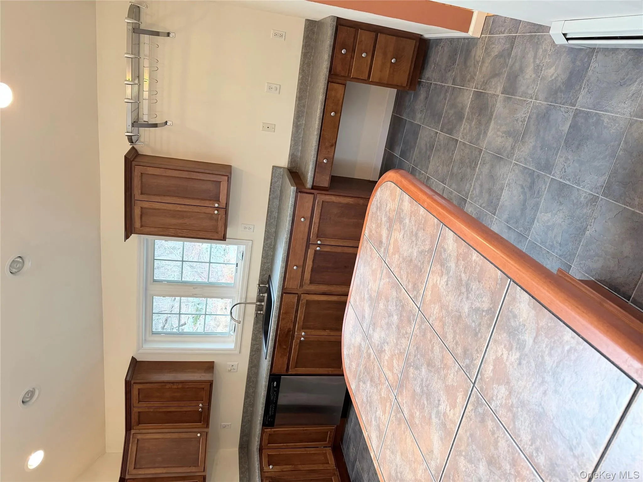 Kitchen with recessed lighting, dishwasher, dark countertops, and brown cabinetry Kitchen with recessed lighting, dishwasher, dark countertops, and brown cabinetry
