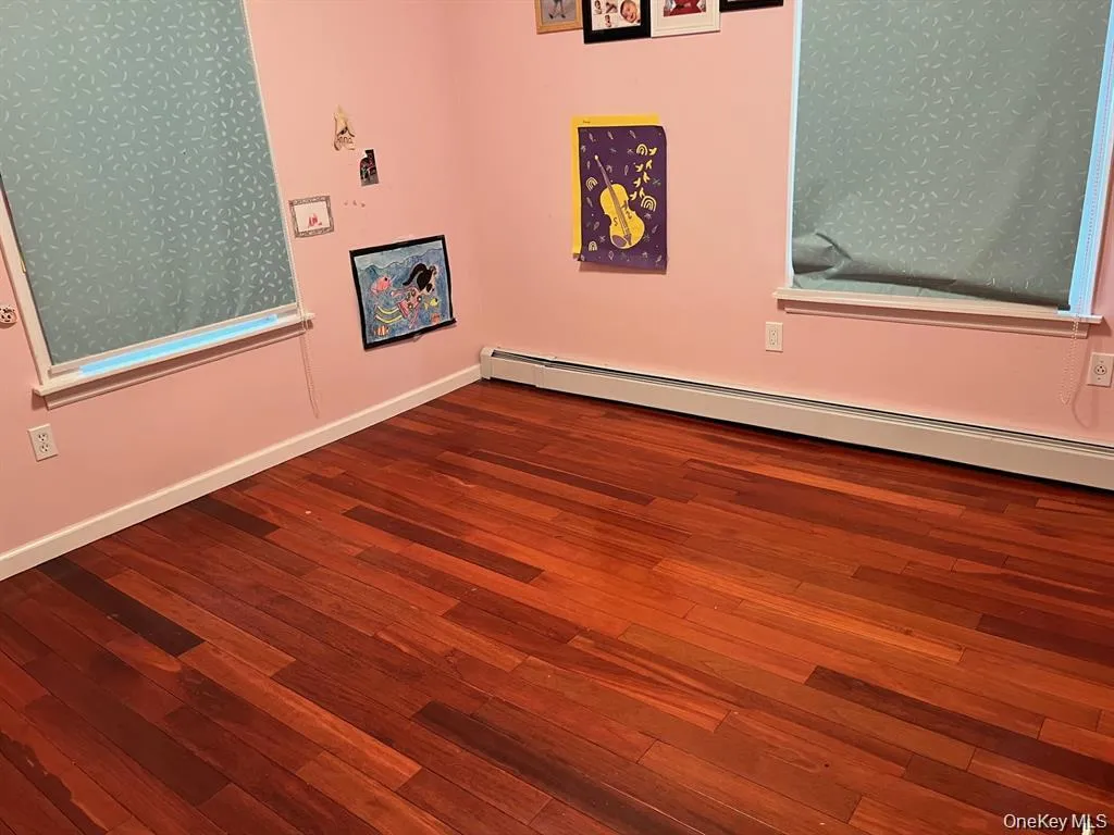 Spare room featuring a baseboard radiator and dark wood-type flooring Spare room featuring a baseboard radiator and dark wood-type flooring