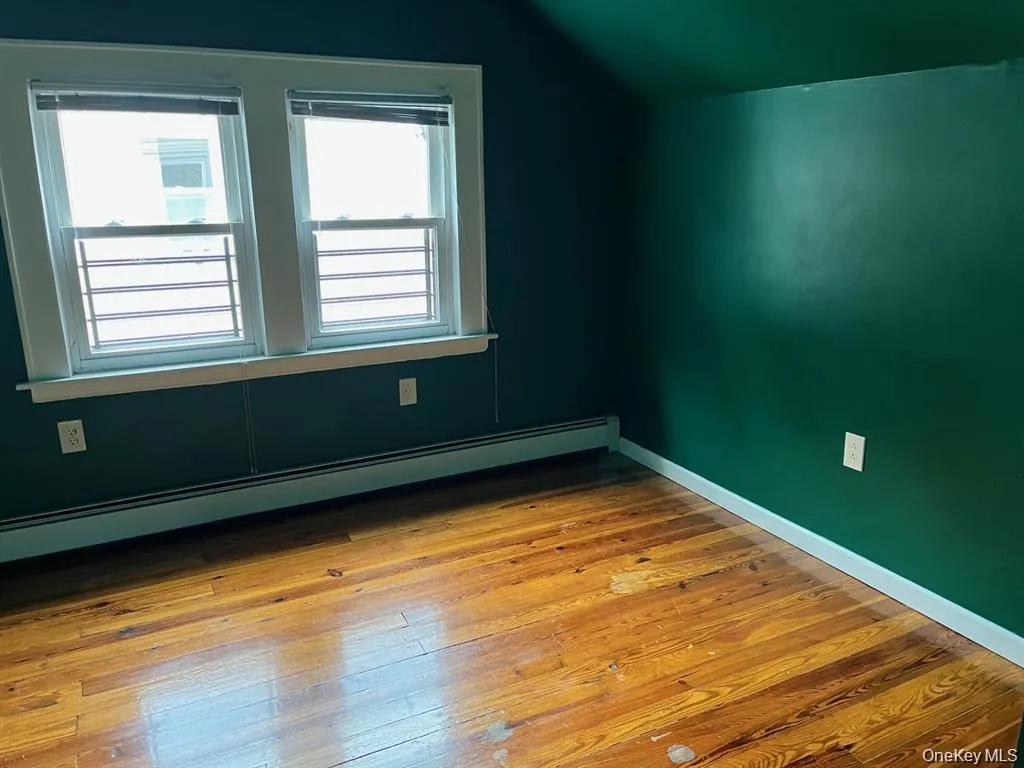 Additional living space featuring a baseboard heating unit, light wood finished floors, and vaulted ceiling Additional living space featuring a baseboard heating unit, light wood finished floors, and vaulted ceiling