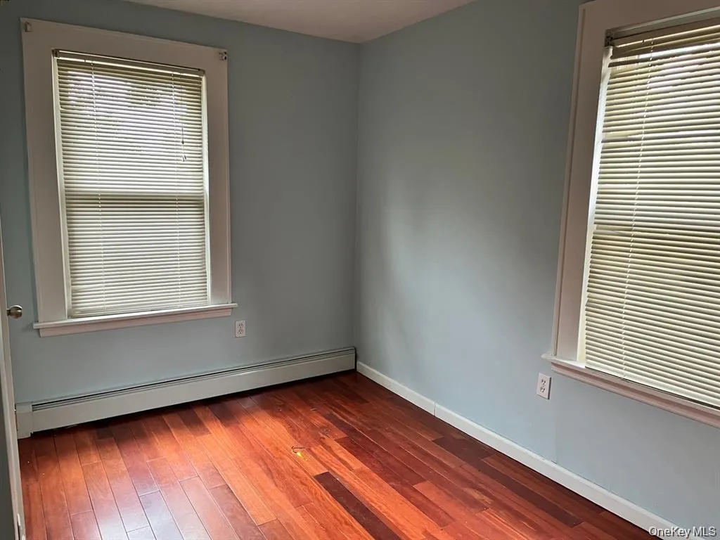 Spare room featuring a baseboard radiator and dark wood finished floors Spare room featuring a baseboard radiator and dark wood finished floors