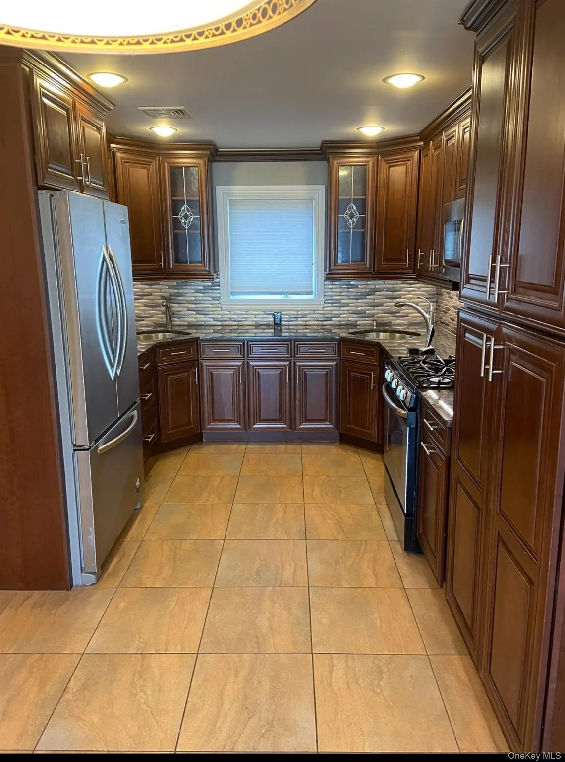 Kitchen with glass insert cabinets, stainless steel appliances, dark stone countertops, decorative backsplash, and recessed lighting Kitchen with glass insert cabinets, stainless steel appliances, dark stone countertops, decorative backsplash, and recessed lighting