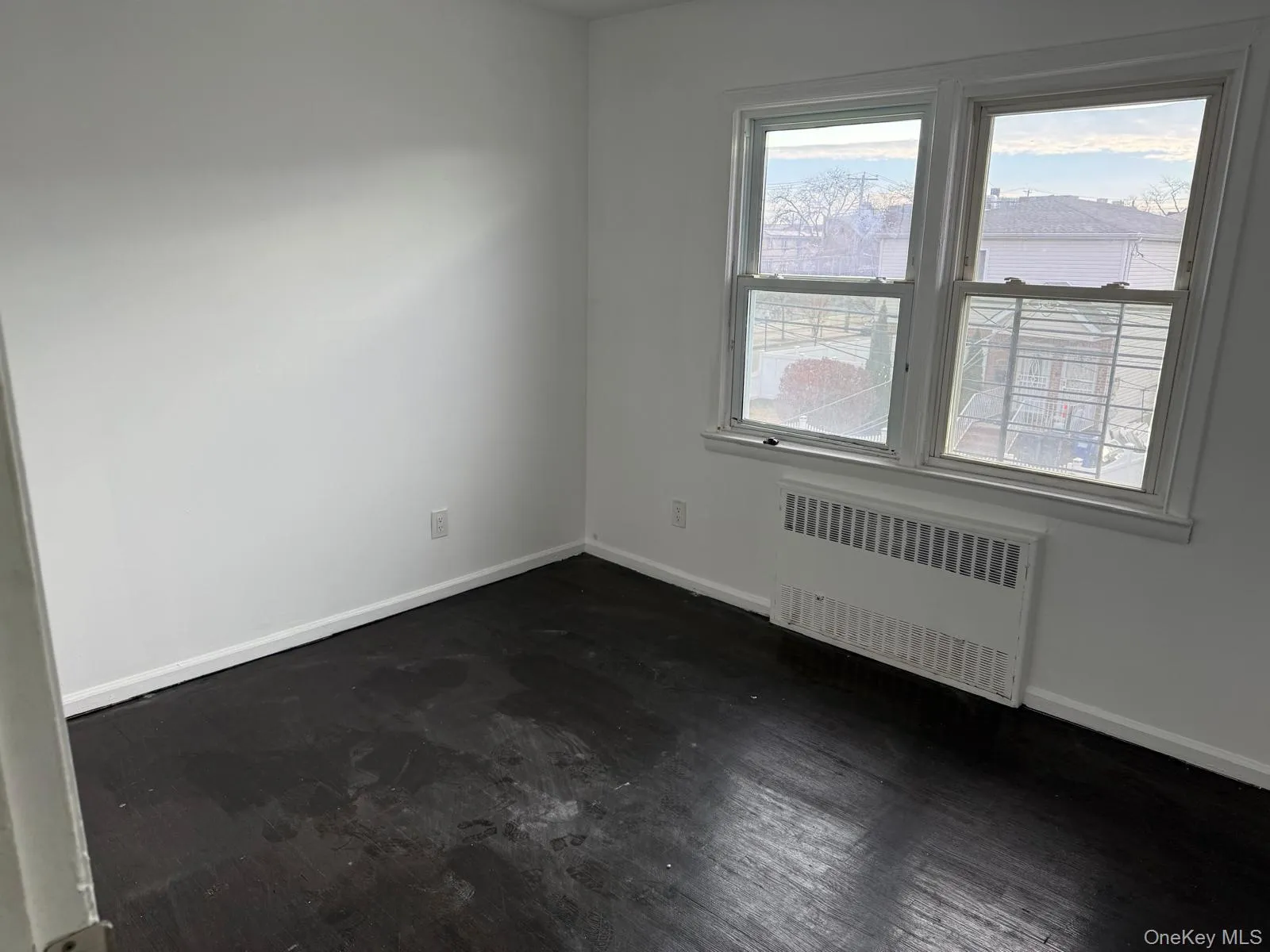 Empty room featuring radiator heating unit and dark wood-type flooring Empty room featuring radiator heating unit and dark wood-type flooring