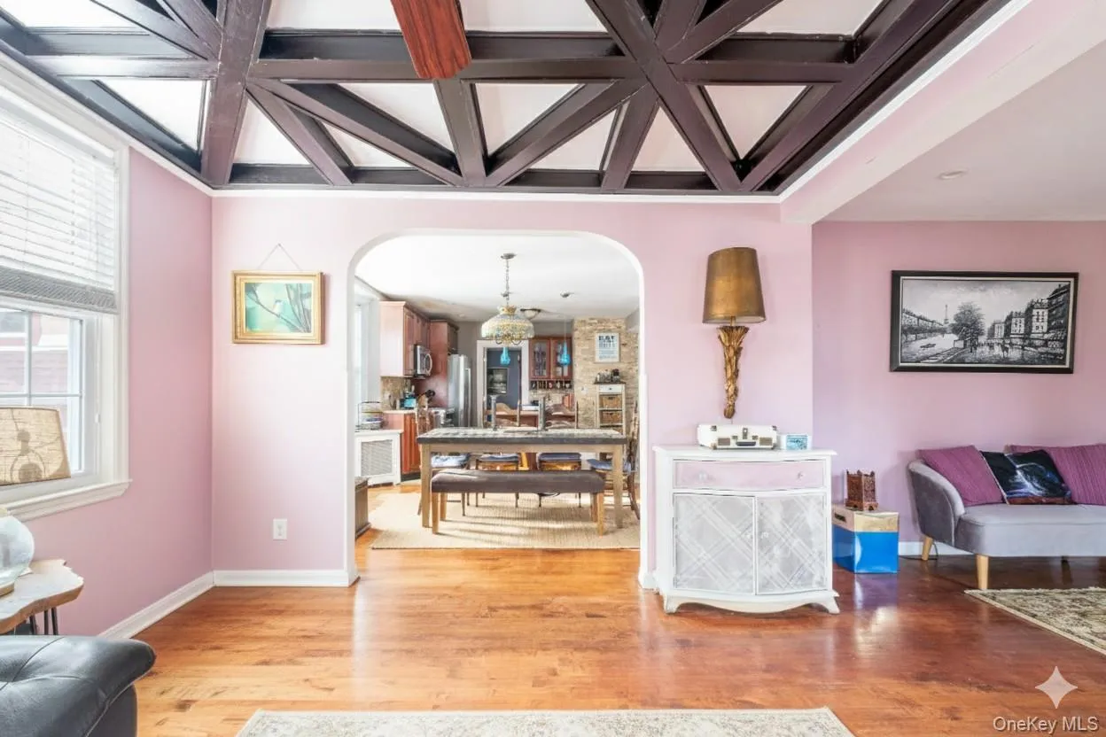 Living area featuring coffered ceiling, light wood-type flooring, arched walkways, and beam ceiling Living area featuring coffered ceiling, light wood-type flooring, arched walkways, and beam ceiling