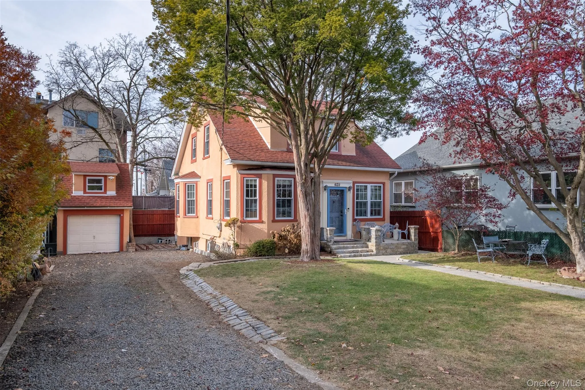 View of front of property with gravel driveway, stucco siding, a garage, and roof with shingles View of front of property with gravel driveway, stucco siding, a garage, and roof with shingles