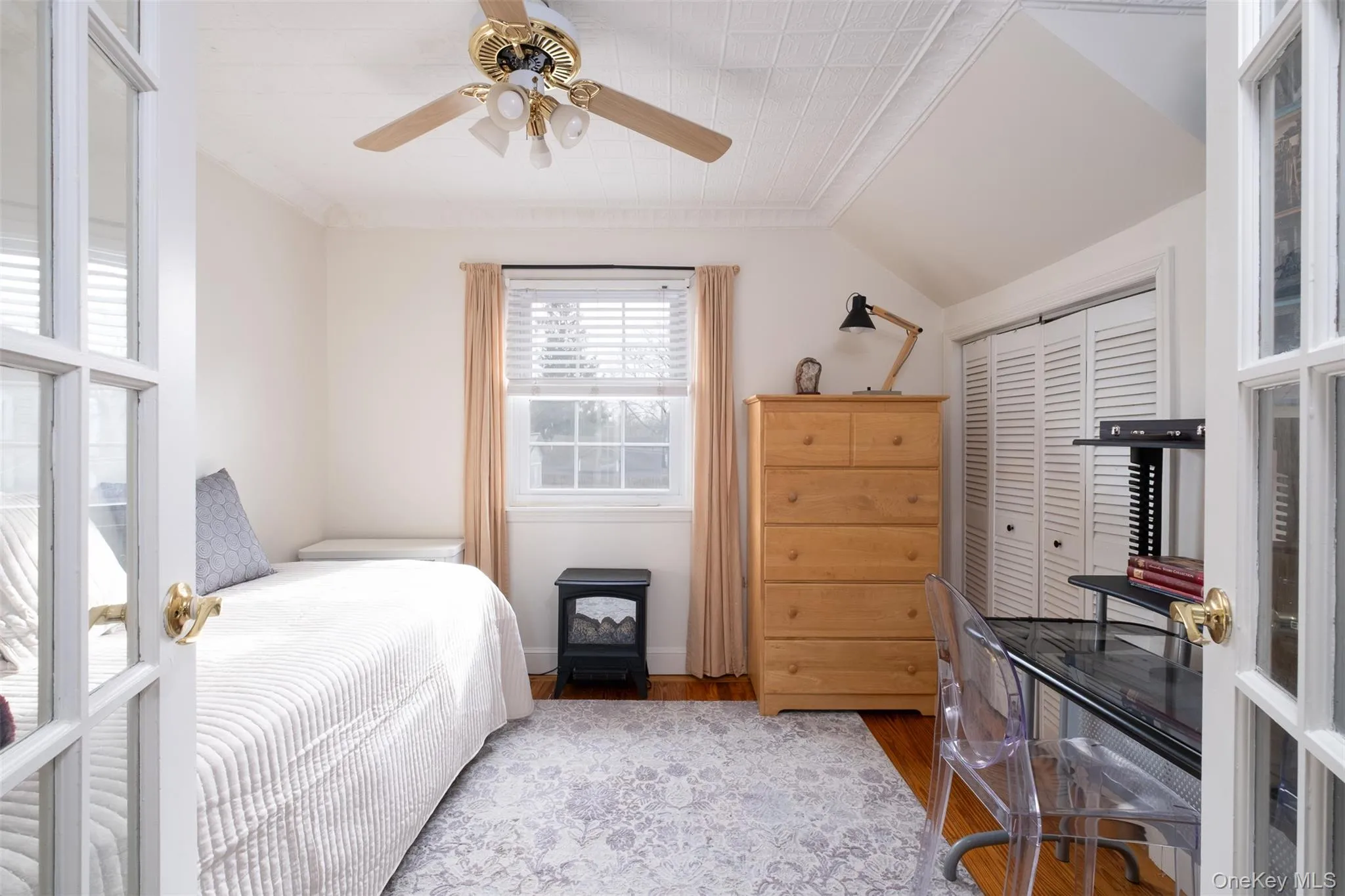 Bedroom featuring wood finished floors, a closet, a ceiling fan, ornamental molding, and lofted ceiling Bedroom featuring wood finished floors, a closet, a ceiling fan, ornamental molding, and lofted ceiling