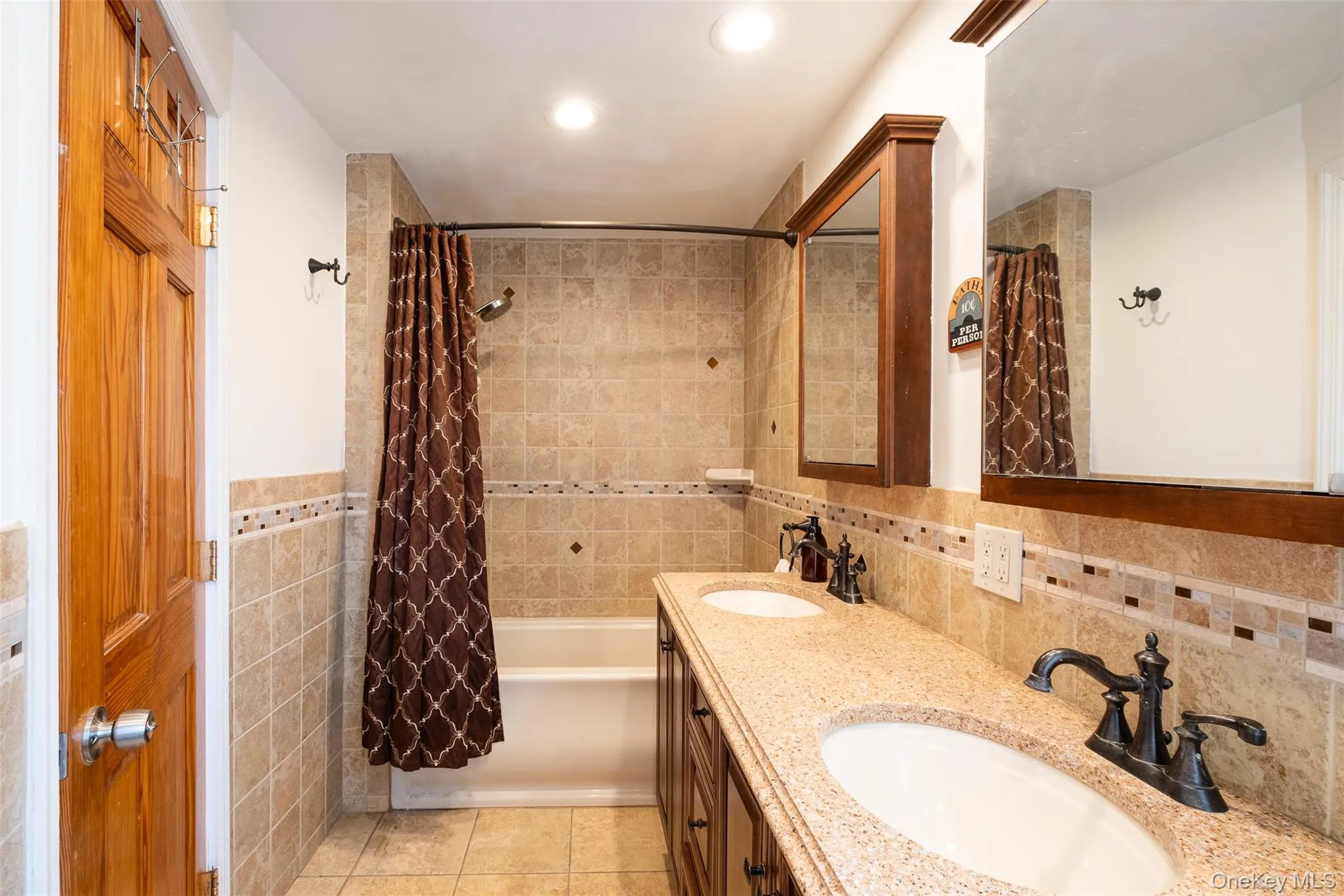 Bathroom featuring shower / tub combo with curtain, double vanity, tile walls, light tile patterned floors, and recessed lighting Bathroom featuring shower / tub combo with curtain, double vanity, tile walls, light tile patterned floors, and recessed lighting