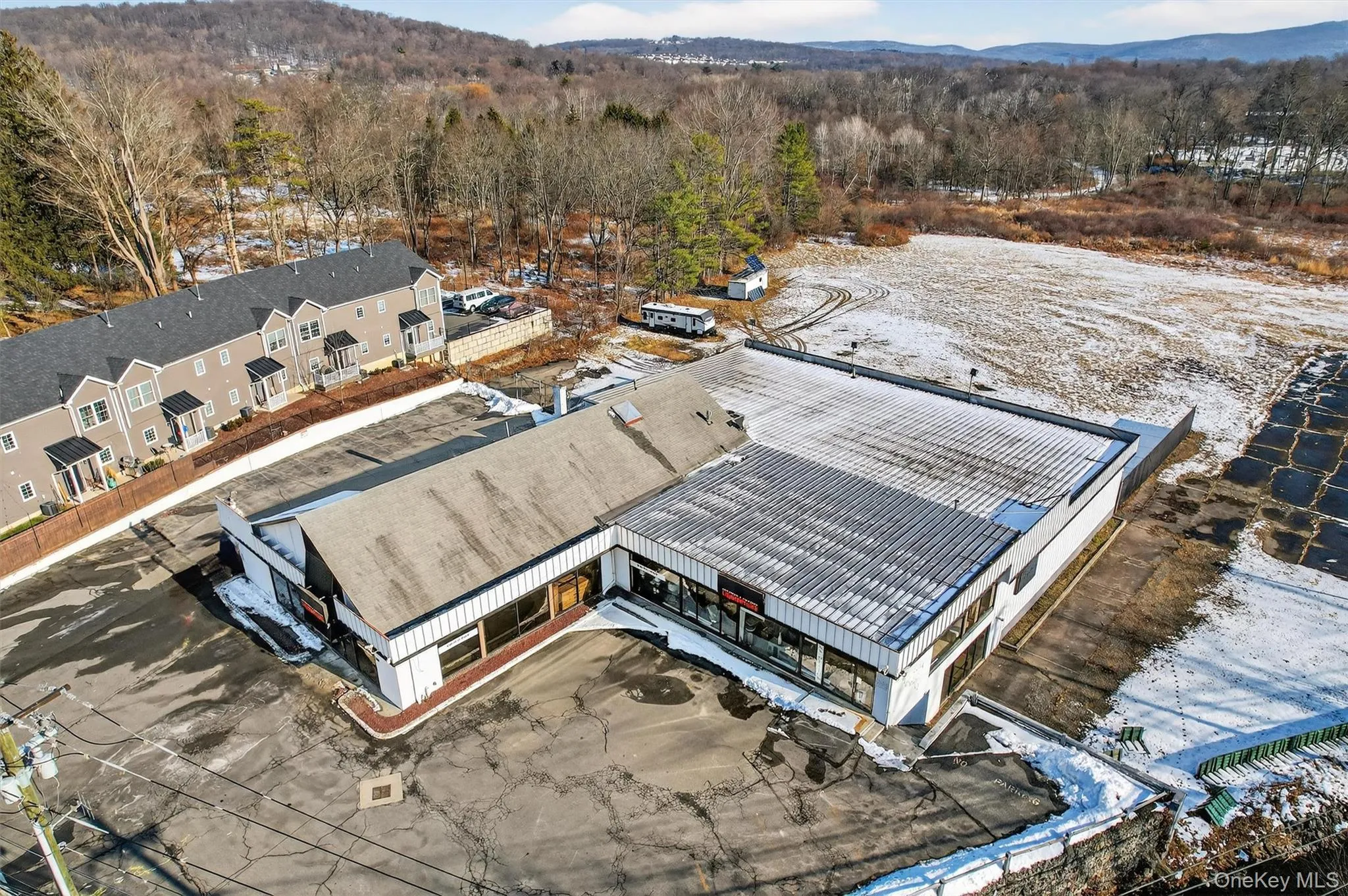 Snowy aerial view featuring a mountain view and a forest view Snowy aerial view featuring a mountain view and a forest view