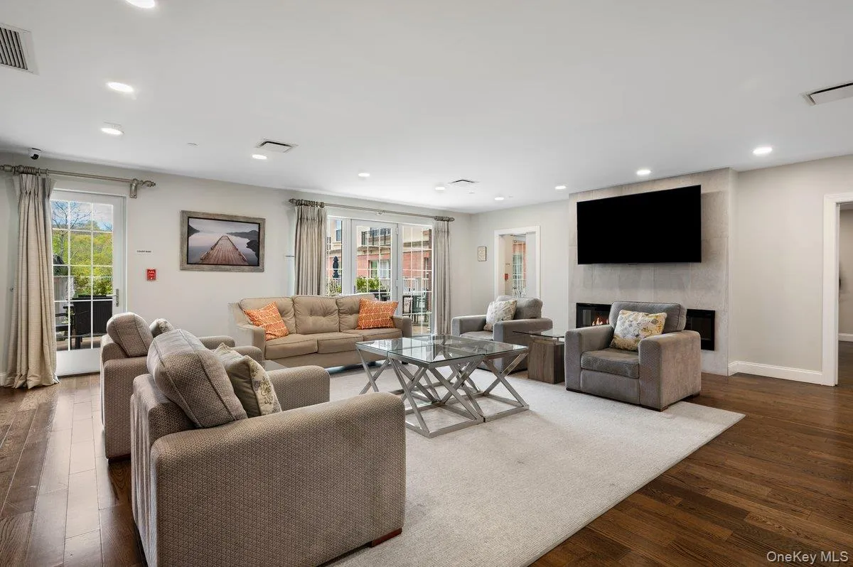 Living room featuring dark wood-style floors, plenty of natural light, a lit fireplace, and recessed lighting Living room featuring dark wood-style floors, plenty of natural light, a lit fireplace, and recessed lighting