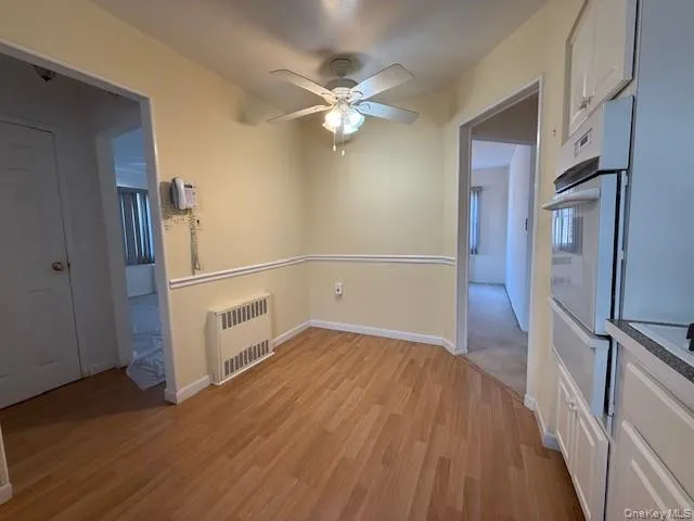 Spare room with light wood-style floors, radiator, and a ceiling fan Spare room with light wood-style floors, radiator, and a ceiling fan