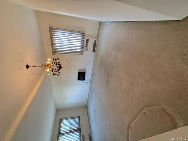 Unfurnished living room featuring carpet, radiator heating unit, a chandelier, and heating unit Unfurnished living room featuring carpet, radiator heating unit, a chandelier, and heating unit