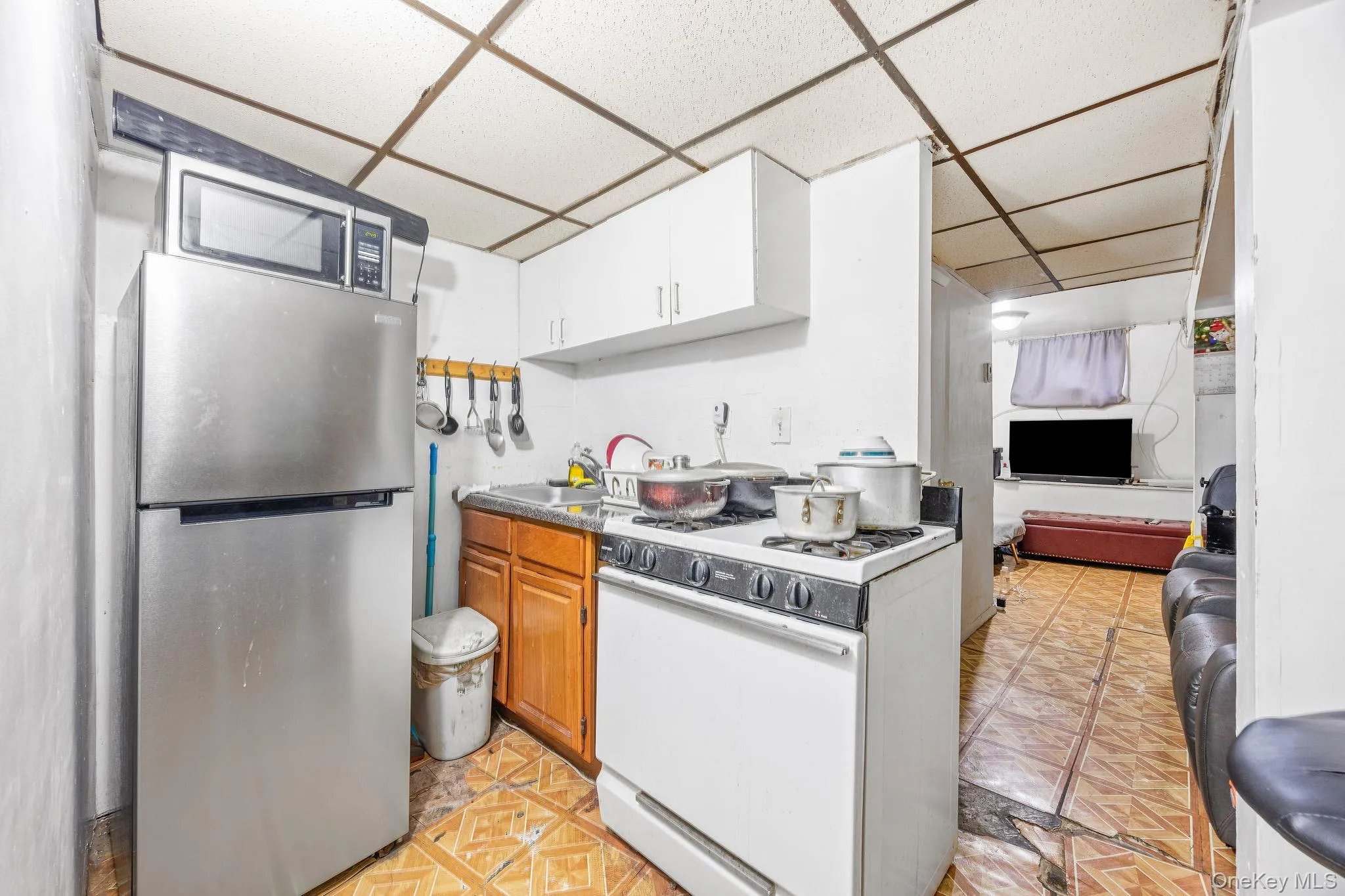 Kitchen featuring appliances with stainless steel finishes, a paneled ceiling, and light floors Kitchen featuring appliances with stainless steel finishes, a paneled ceiling, and light floors