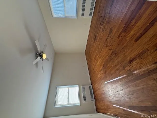 Unfurnished room with radiator, dark wood-style flooring, and ceiling fan Unfurnished room with radiator, dark wood-style flooring, and ceiling fan