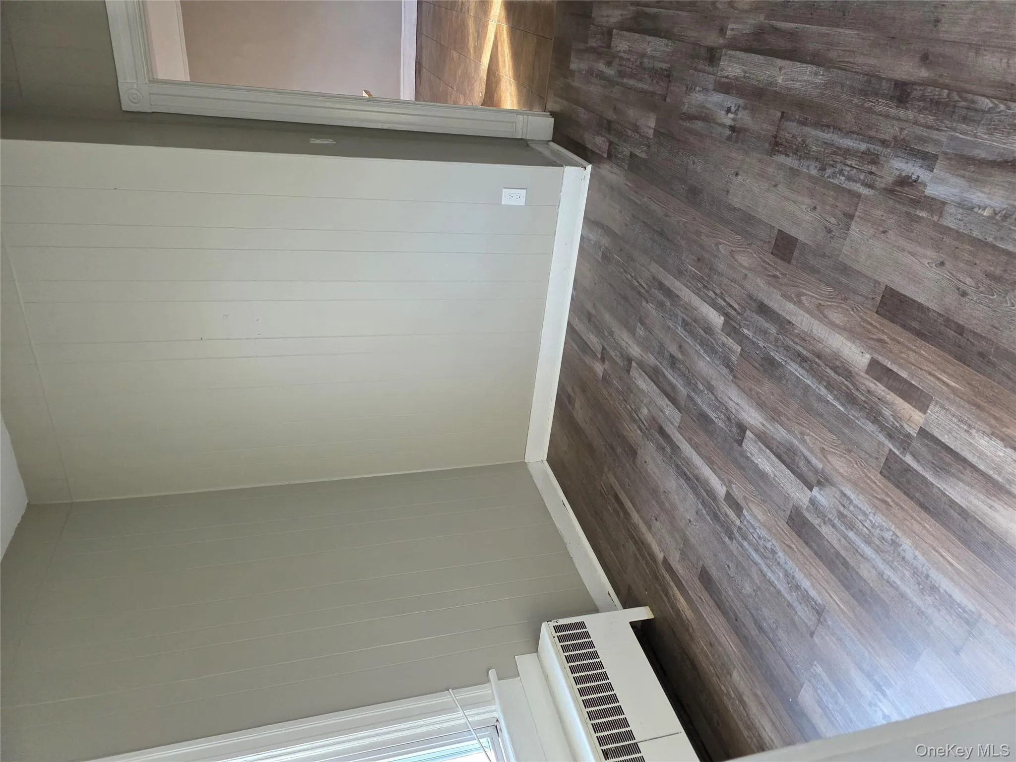 Unfurnished room with dark wood finished floors, radiator, and wood walls Unfurnished room with dark wood finished floors, radiator, and wood walls