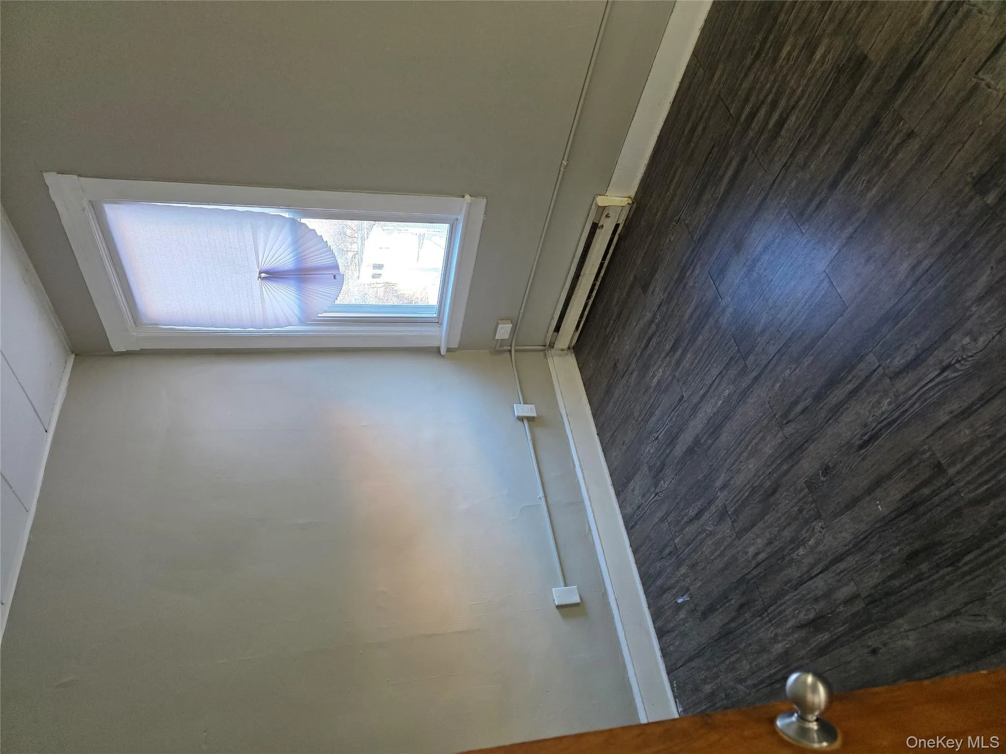 Empty room with a baseboard heating unit and dark wood-type flooring Empty room with a baseboard heating unit and dark wood-type flooring