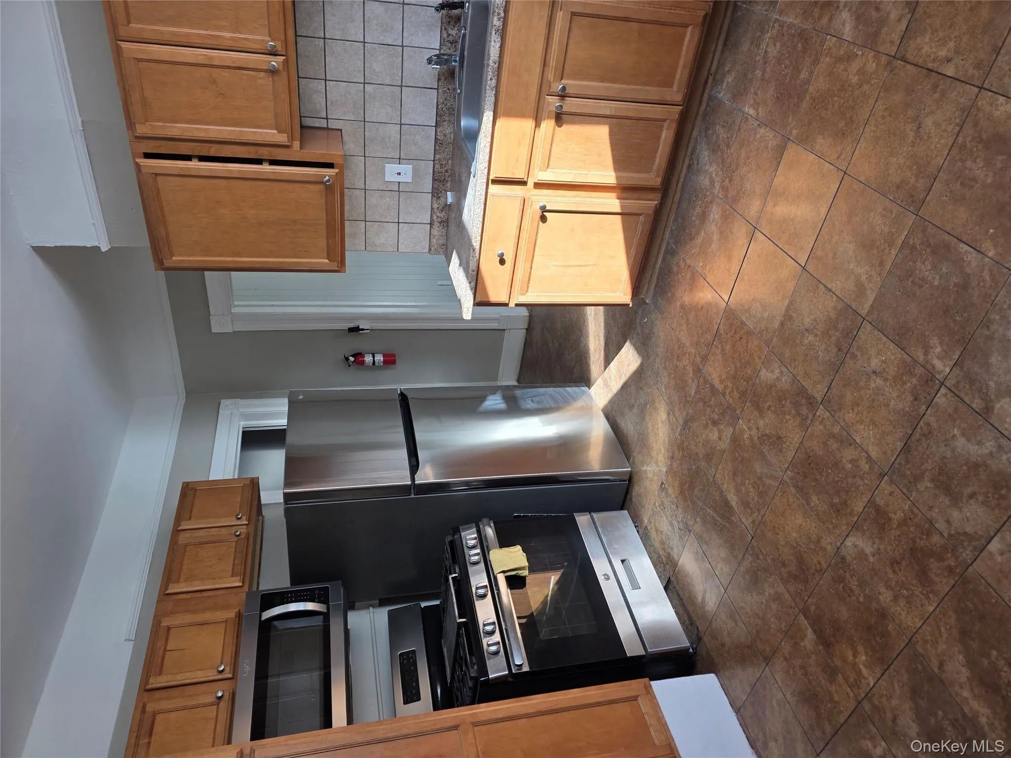 Kitchen with brown cabinets, range, backsplash, and freestanding refrigerator Kitchen with brown cabinets, range, backsplash, and freestanding refrigerator