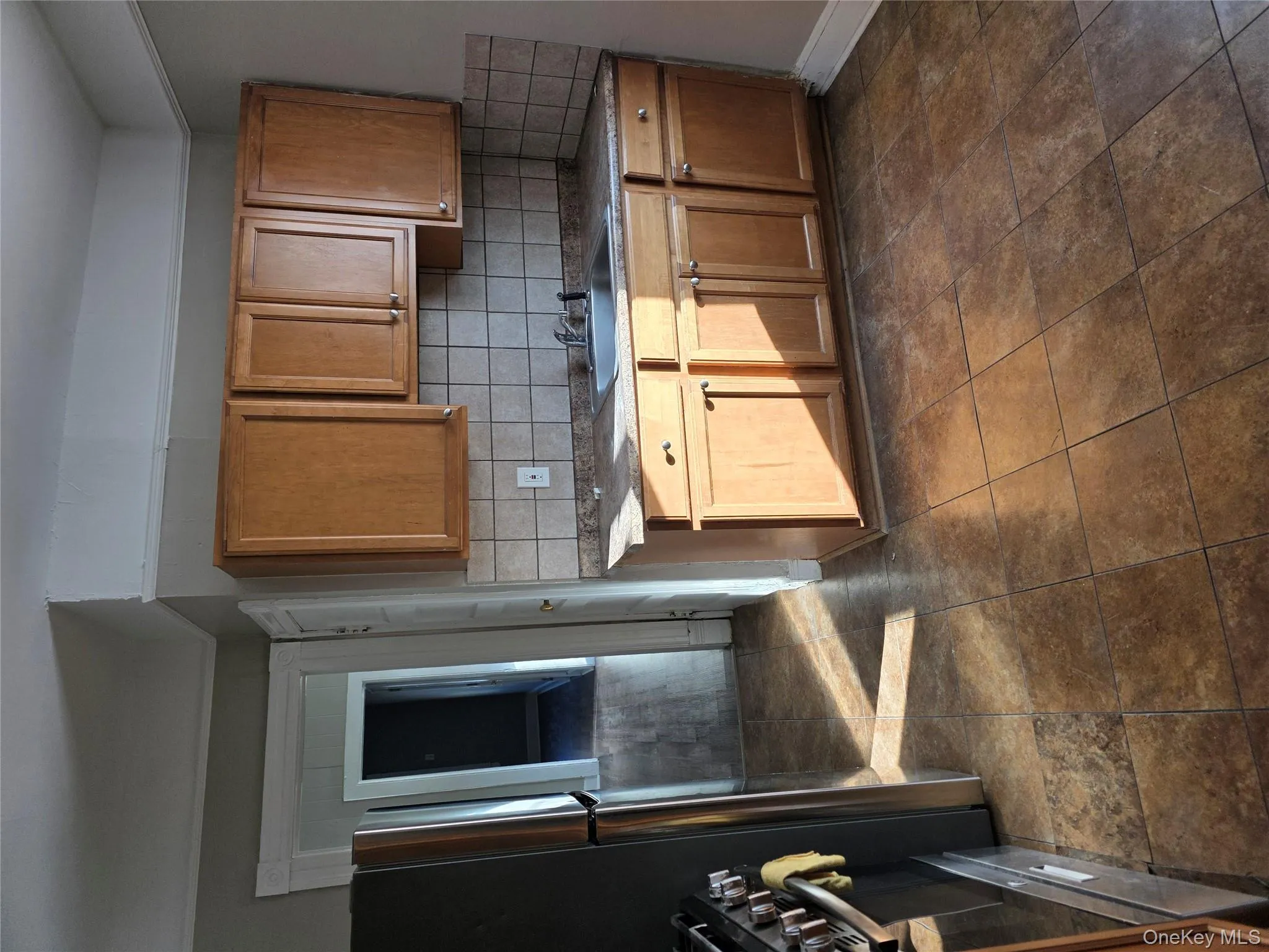 Kitchen with stove, brown cabinetry, tasteful backsplash, dark countertops, and refrigerator Kitchen with stove, brown cabinetry, tasteful backsplash, dark countertops, and refrigerator