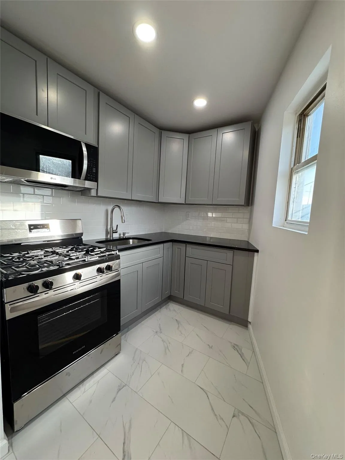 Kitchen featuring gray cabinetry, stainless steel appliances, decorative backsplash, light marble finish flooring, and recessed lighting Kitchen featuring gray cabinetry, stainless steel appliances, decorative backsplash, light marble finish flooring, and recessed lighting