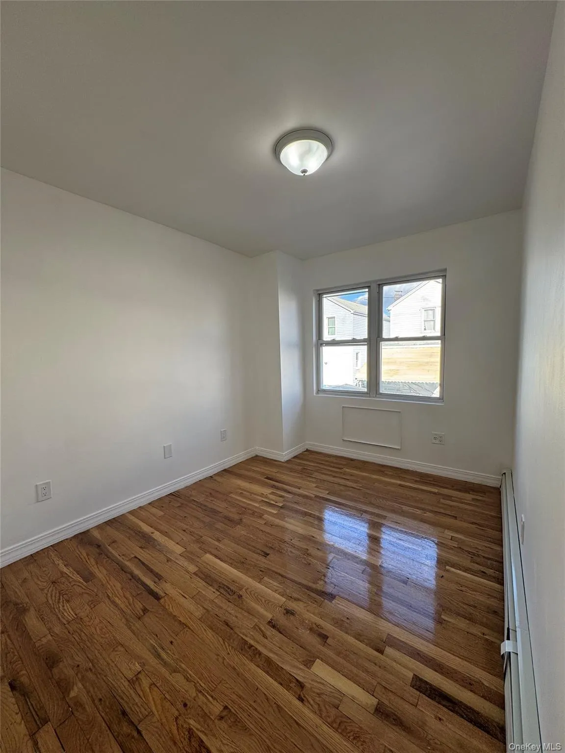 Spare room with dark wood-style floors and baseboard heating Spare room with dark wood-style floors and baseboard heating