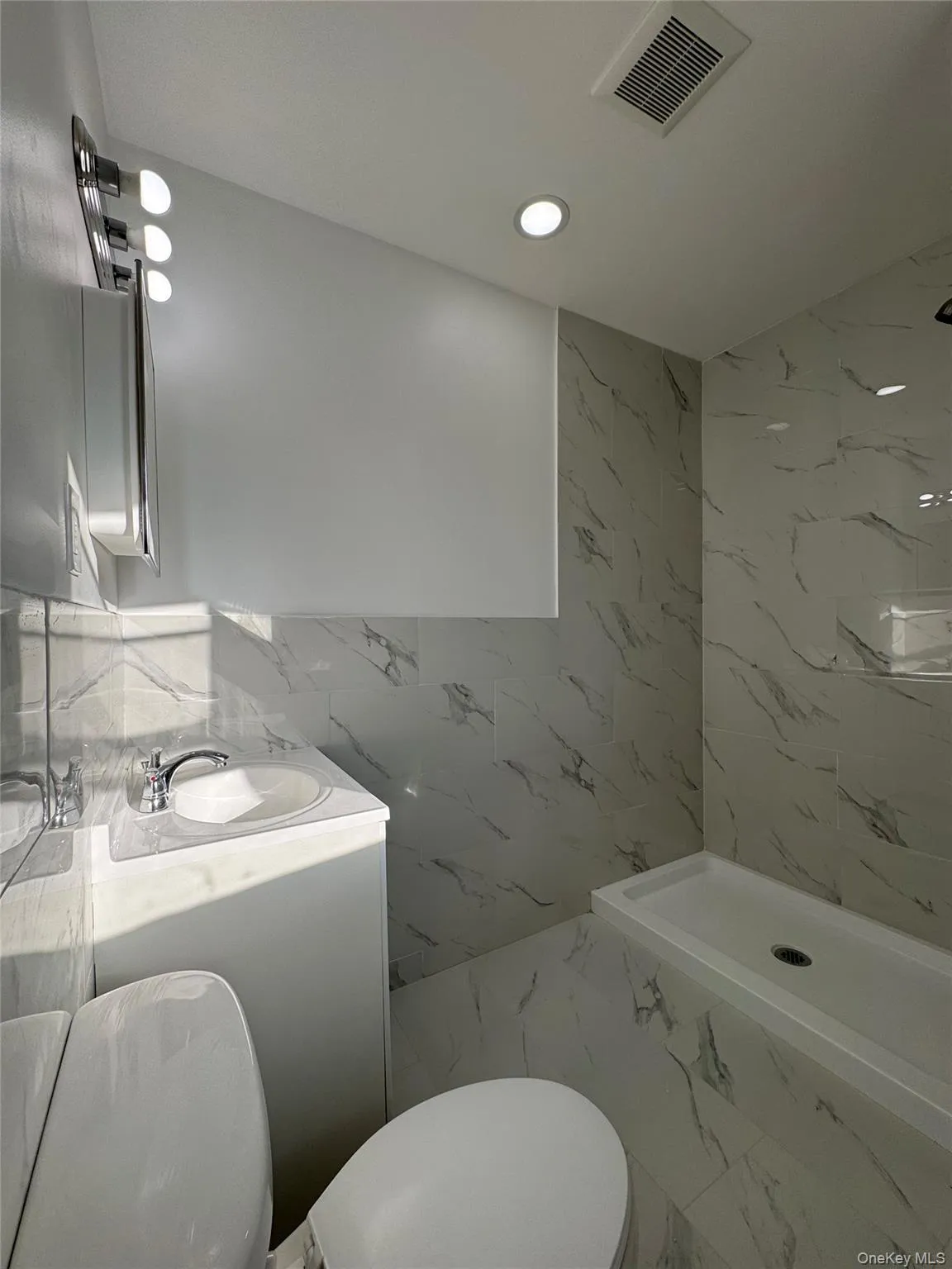 Full bathroom featuring tile walls, marble finish floors, a marble finish shower, recessed lighting, and vanity Full bathroom featuring tile walls, marble finish floors, a marble finish shower, recessed lighting, and vanity