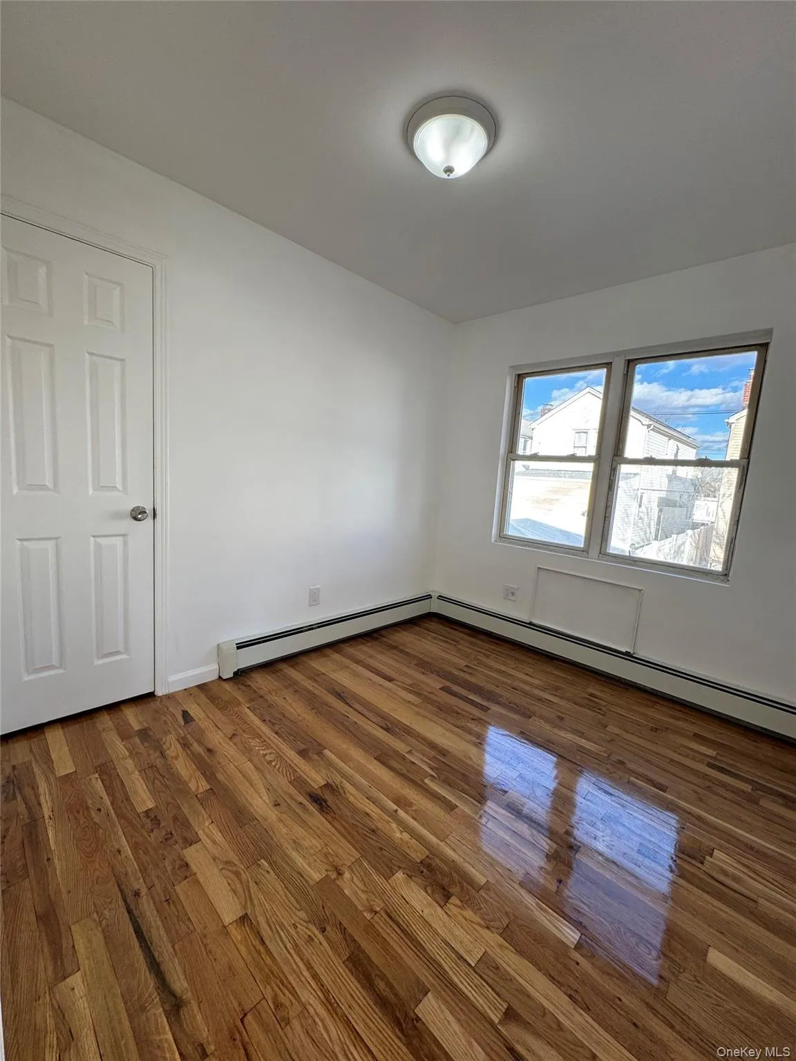 Spare room featuring dark wood-style floors and a baseboard radiator Spare room featuring dark wood-style floors and a baseboard radiator